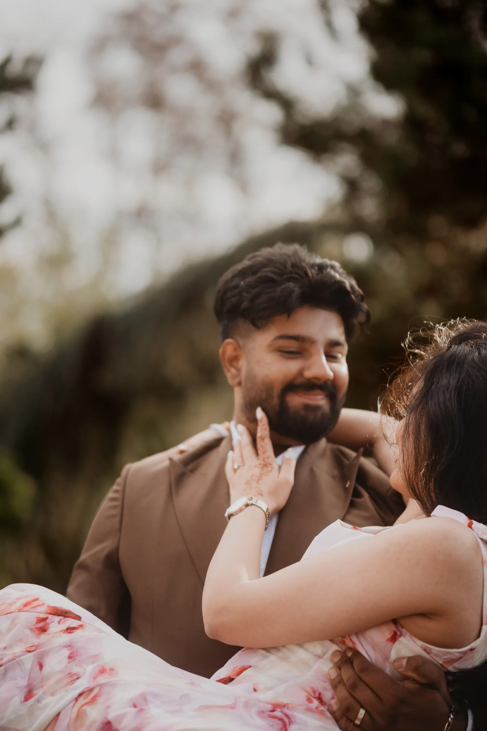 The bride cradled in Kamal's arms, her henna hand resting along his jaw, by AD Photography