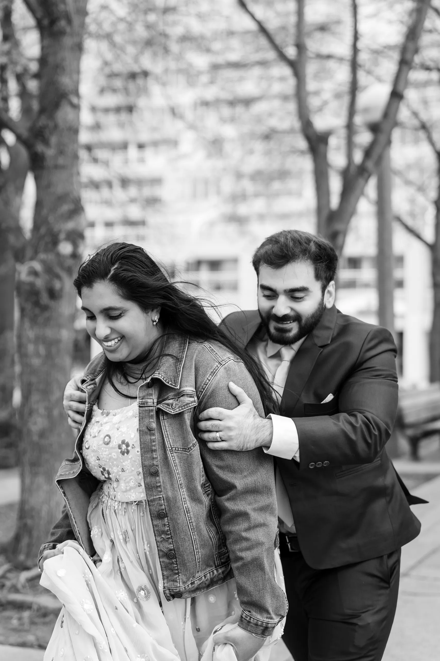 Black and white candid of Abdullah and Nadia laughing together on a walk through a Toronto park, by AD Photography