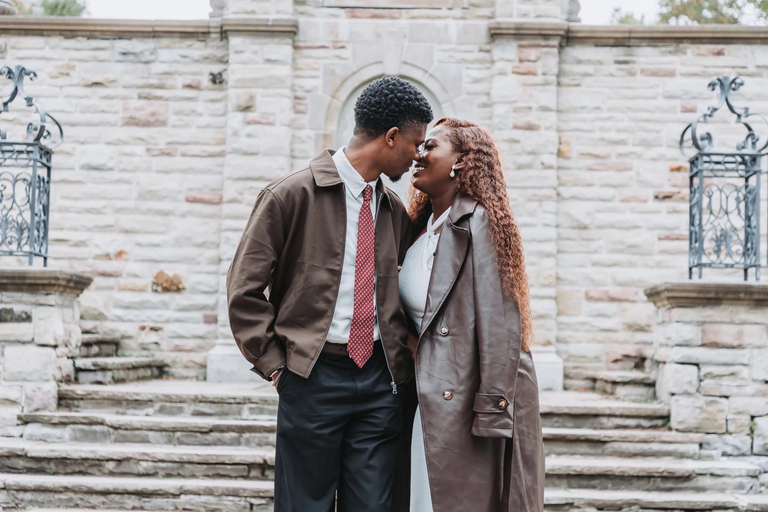 Richie and Aimee nose to nose in front of the arched stone niche and iron railings, by AD Photography