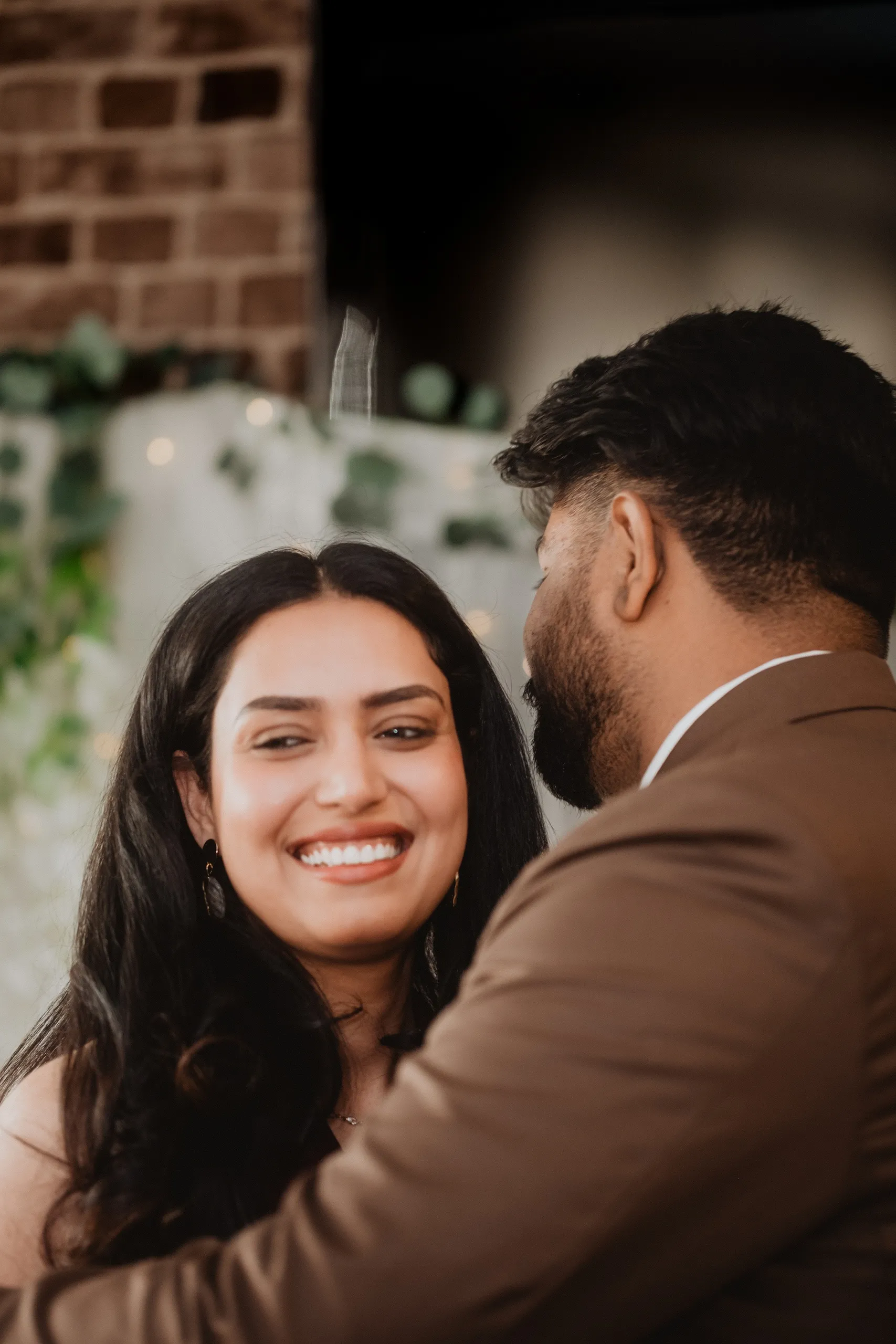 Mehak smiling over Kamal's shoulder in front of fairy lights and trailing greenery, by AD Photography