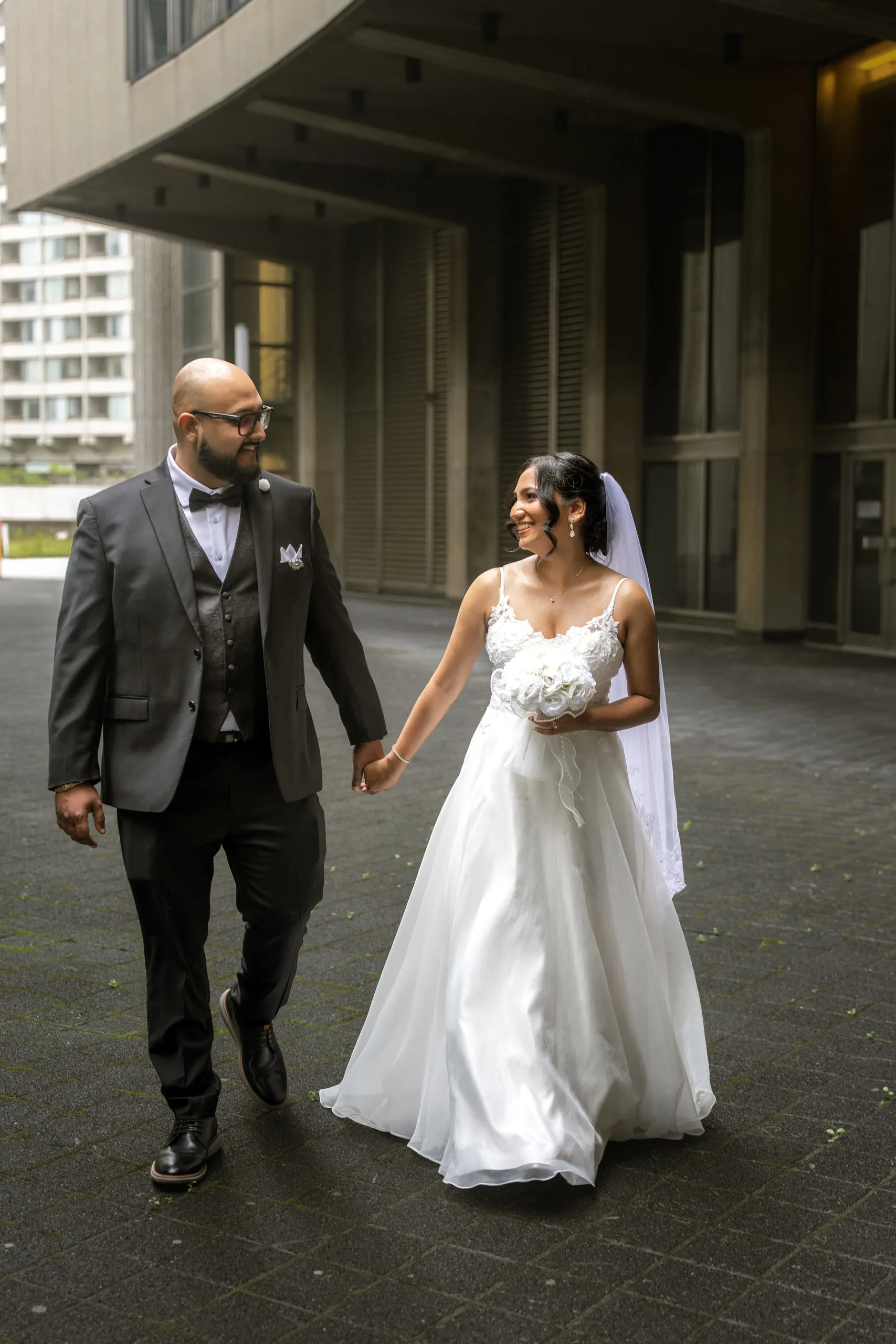 Bride and groom walk the colonnade at Toronto City Hall, by AD Photography