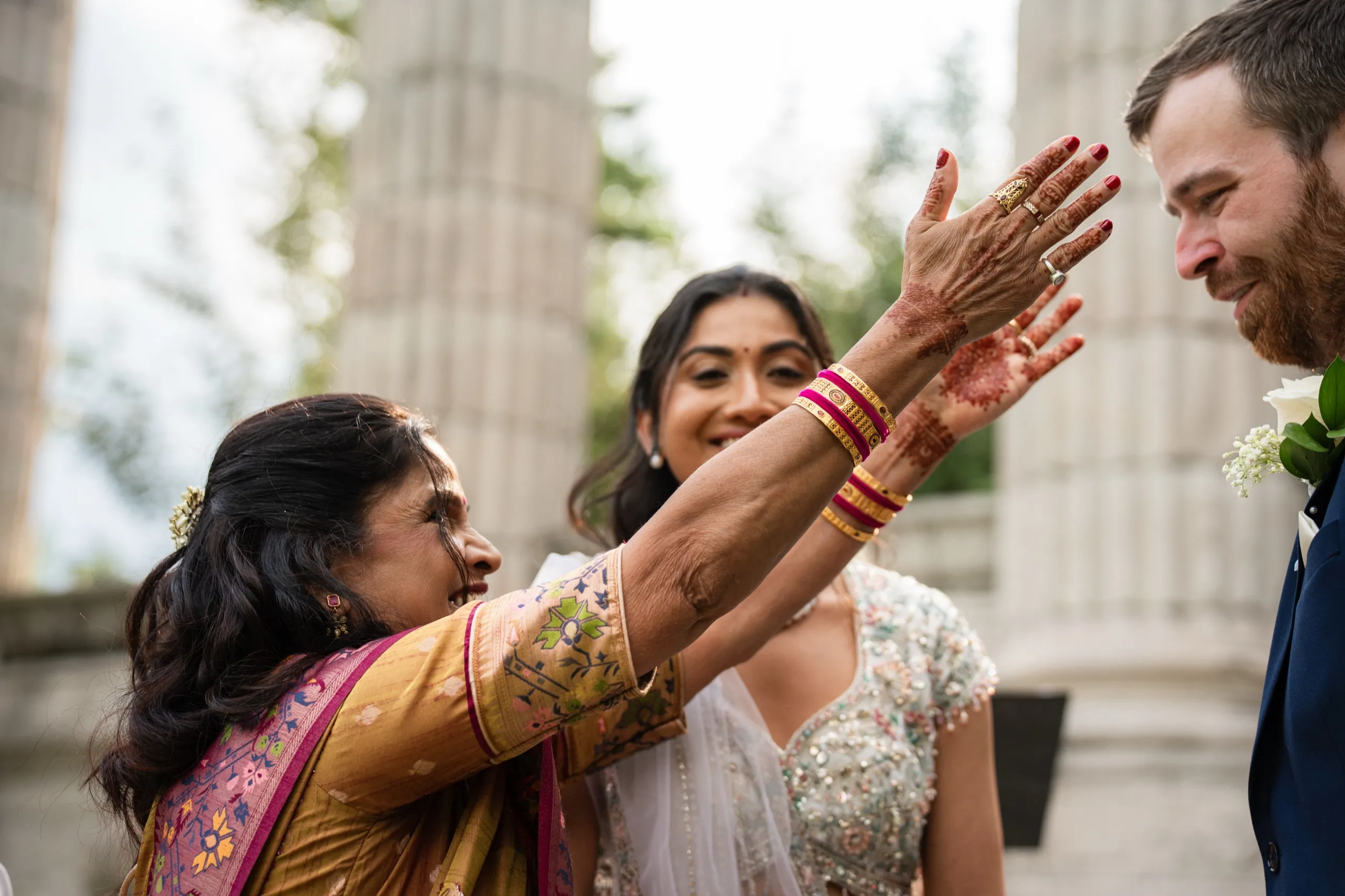 Nidhi's mother reaches up to bless Derek, henna still fresh across her palm and wrist., by AD Photography