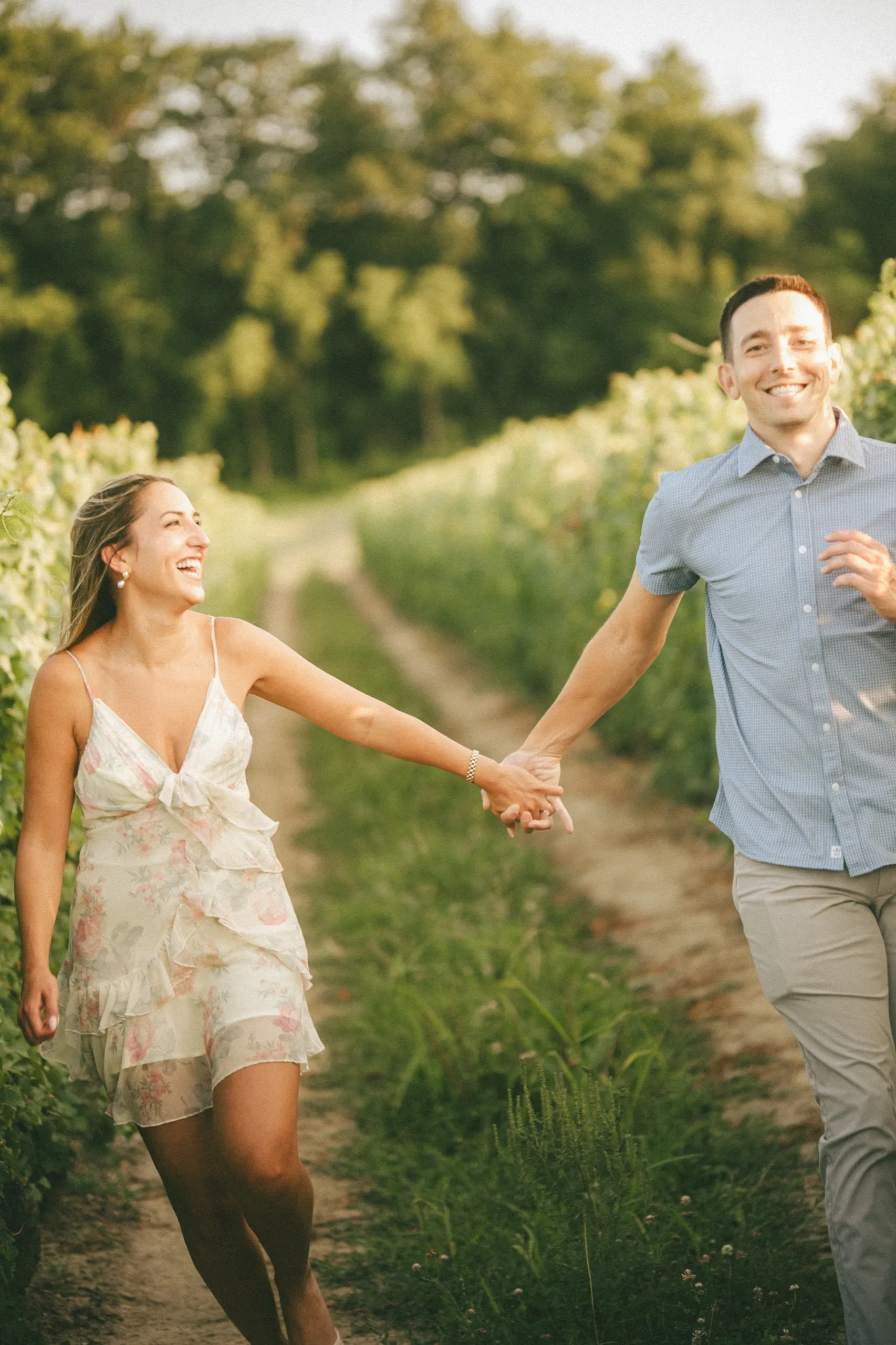 Ashley and Donald running hand in hand down a vineyard row at Château des Charmes, by AD Photography
