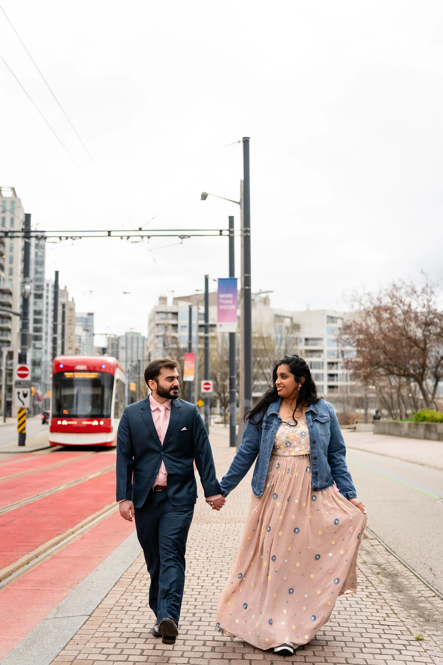 Abdullah and Nadia walk along a Toronto avenue as a red streetcar passes behind them, by AD Photography