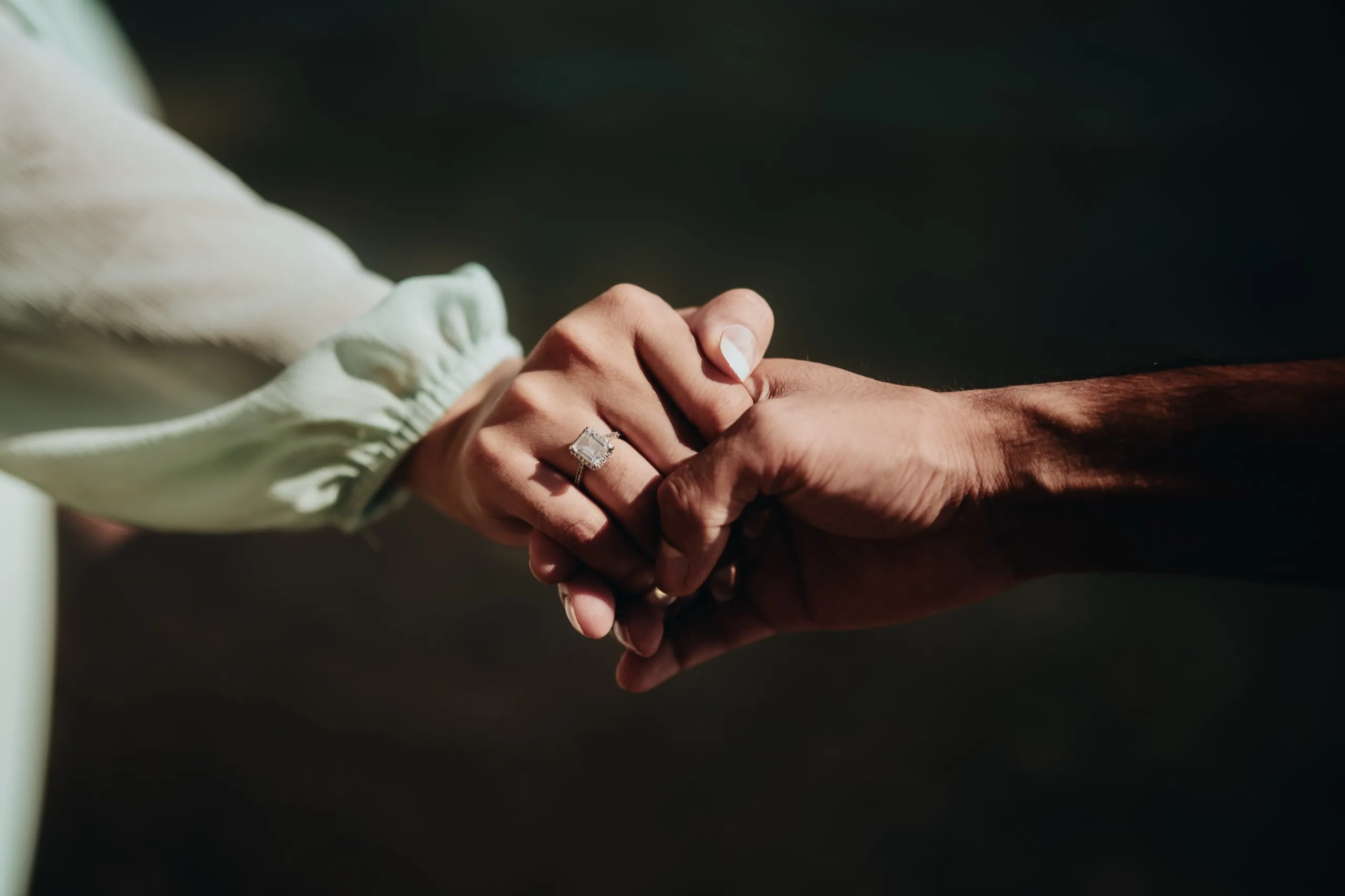 Close detail of Swati's emerald cut engagement ring as their clasped hands catch the light, by AD Photography
