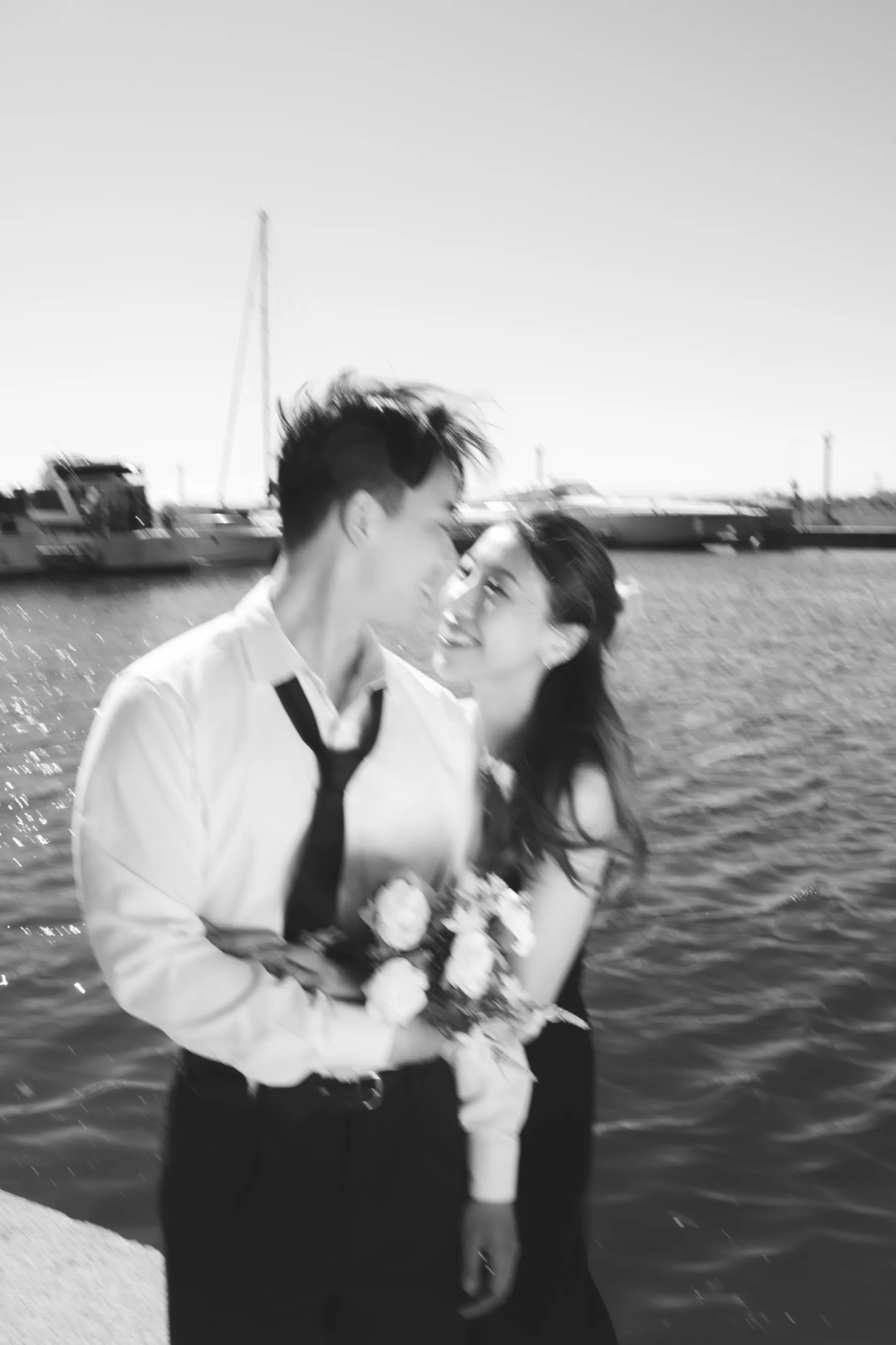 A black and white frame of Josie and Nelson windswept along the Toronto waterfront, by AD Photography