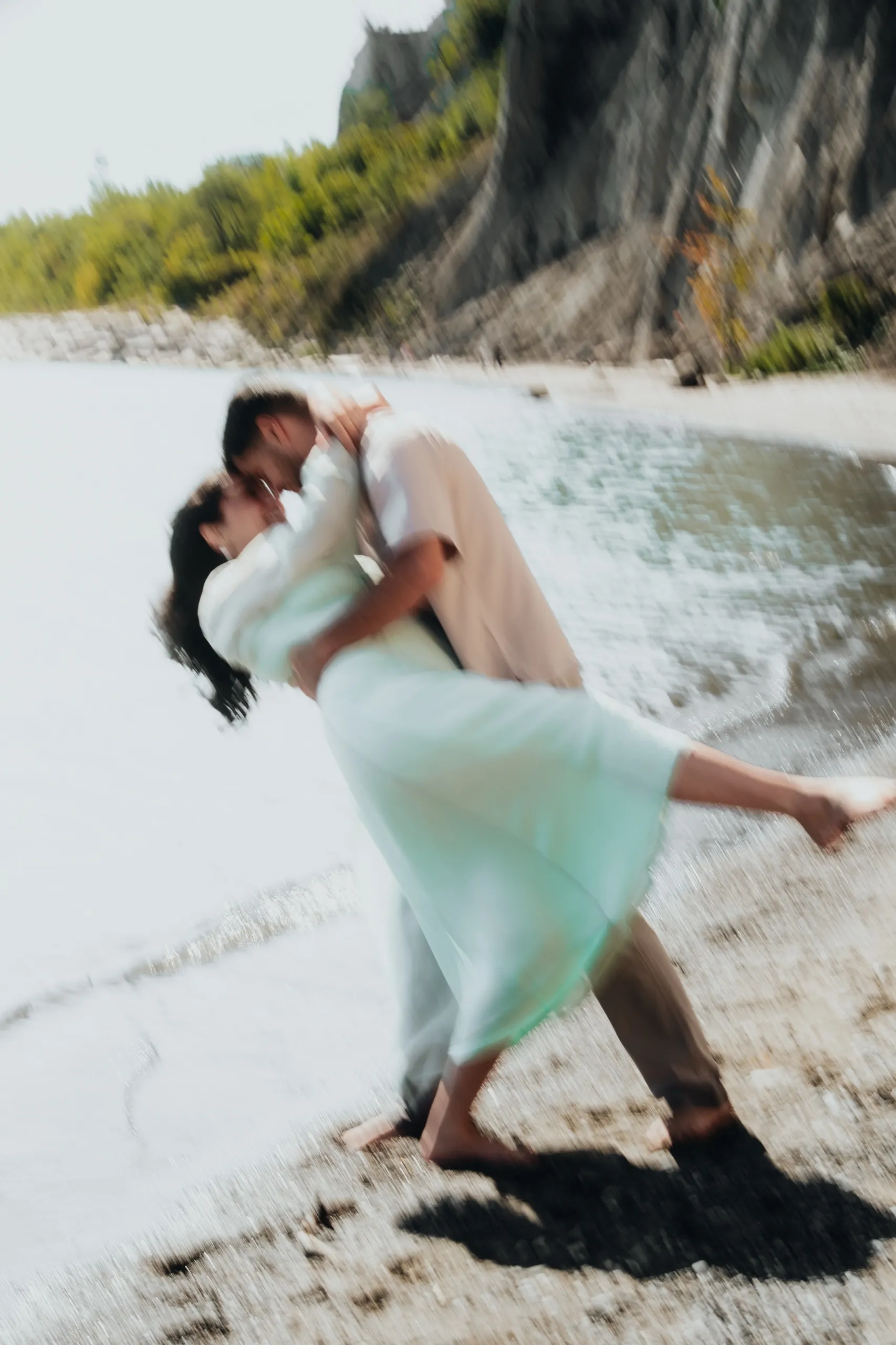 Ghosted slow shutter dip at the shoreline, the couple dissolving into mint and surf, by AD Photography
