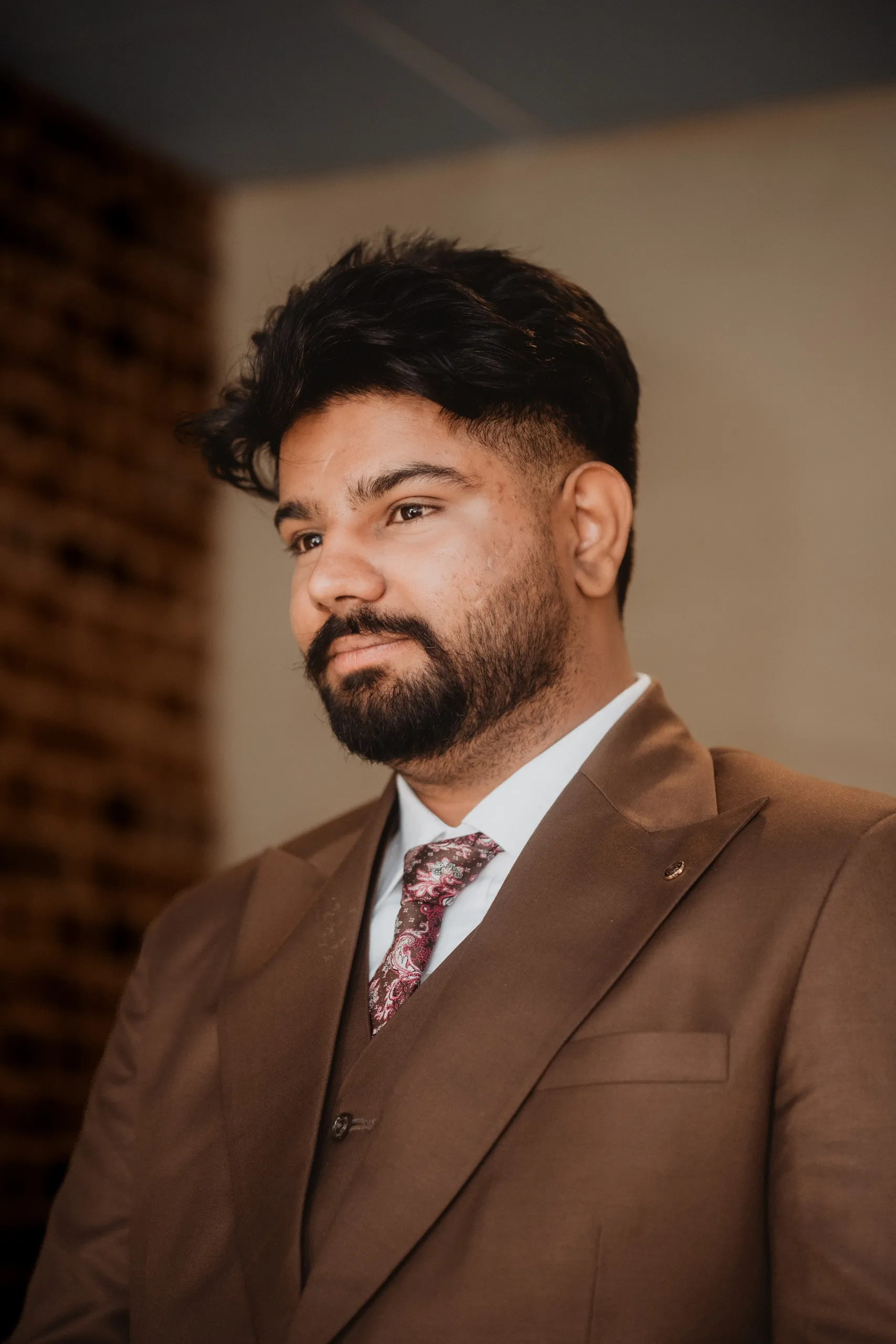 Kamal in a brown three piece suit and floral tie before the civil ceremony, by AD Photography