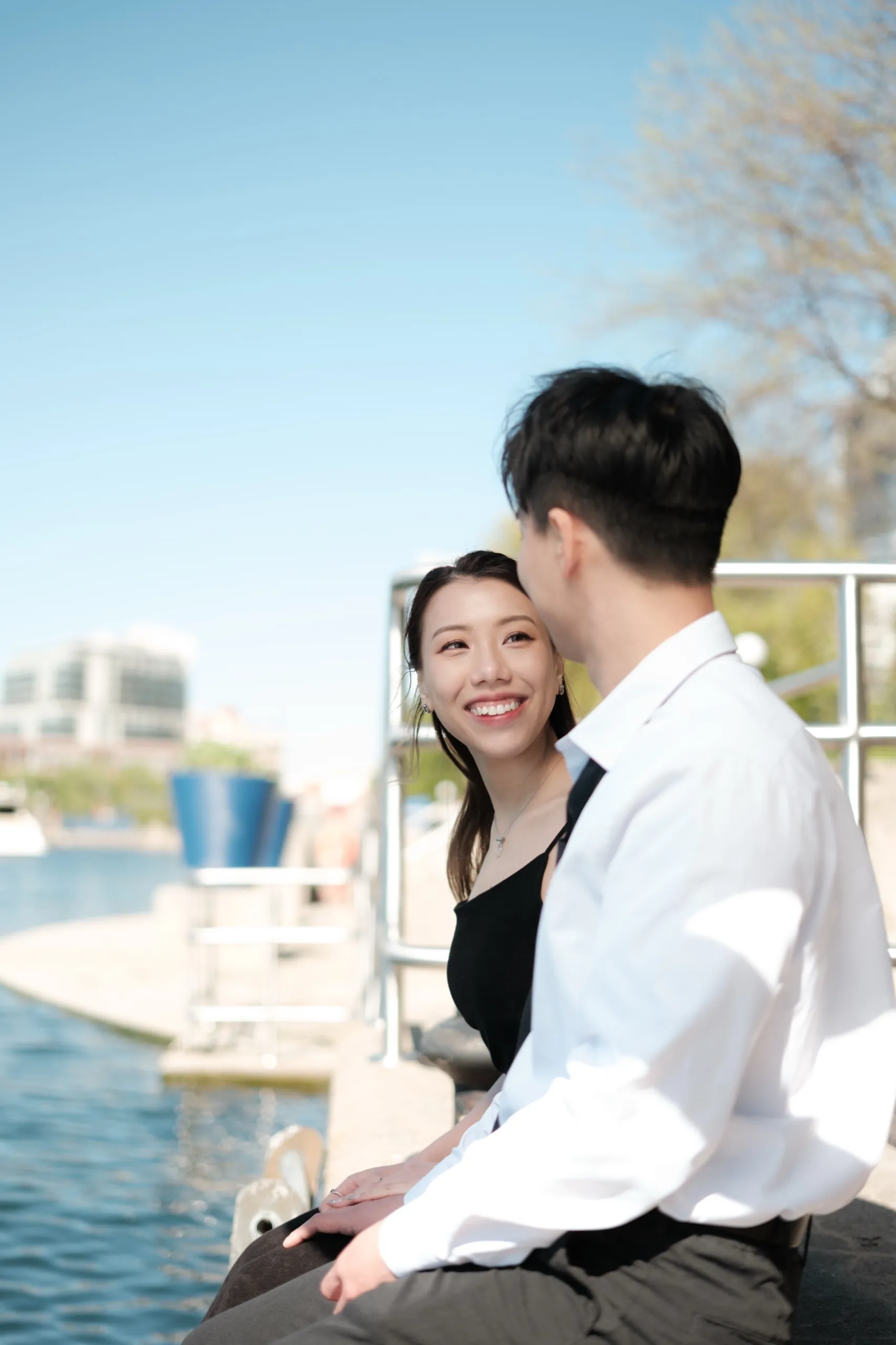 Josie leans back into Nelson with a wide smile in golden waterfront light, by AD Photography