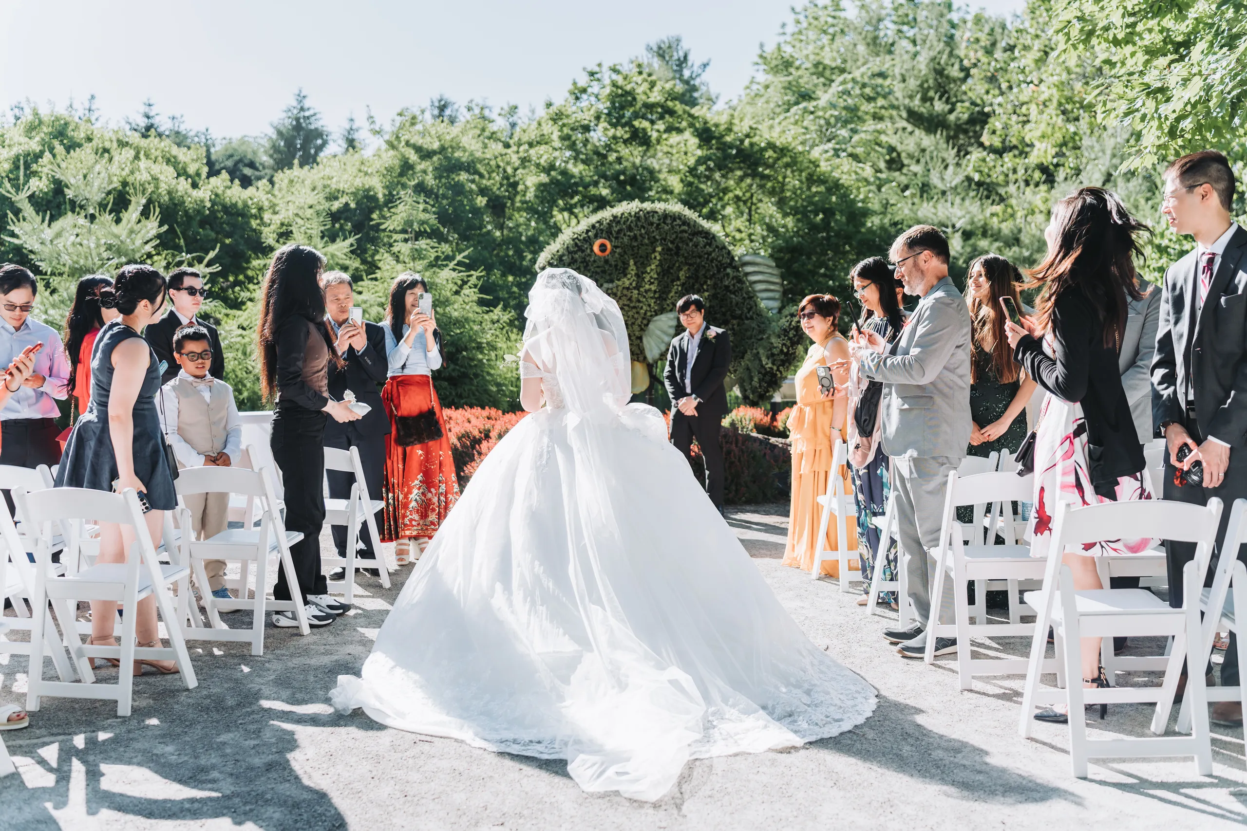Karen walking the aisle with her veil lifted by the breeze at the Niagara Parks Botanical Gardens, by AD Photography