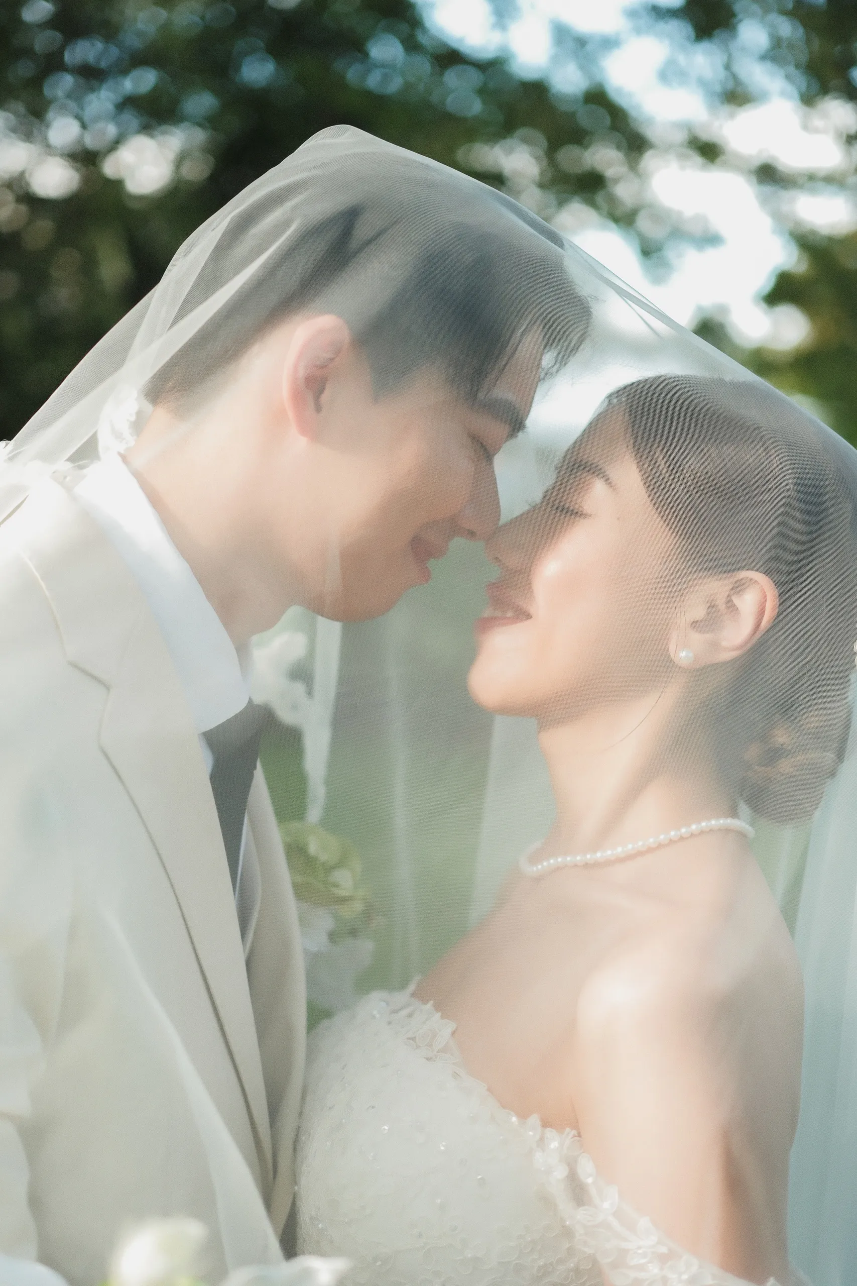 A veiled kiss in soft blur, Josie and Nelson with eyes closed and smiling, by AD Photography