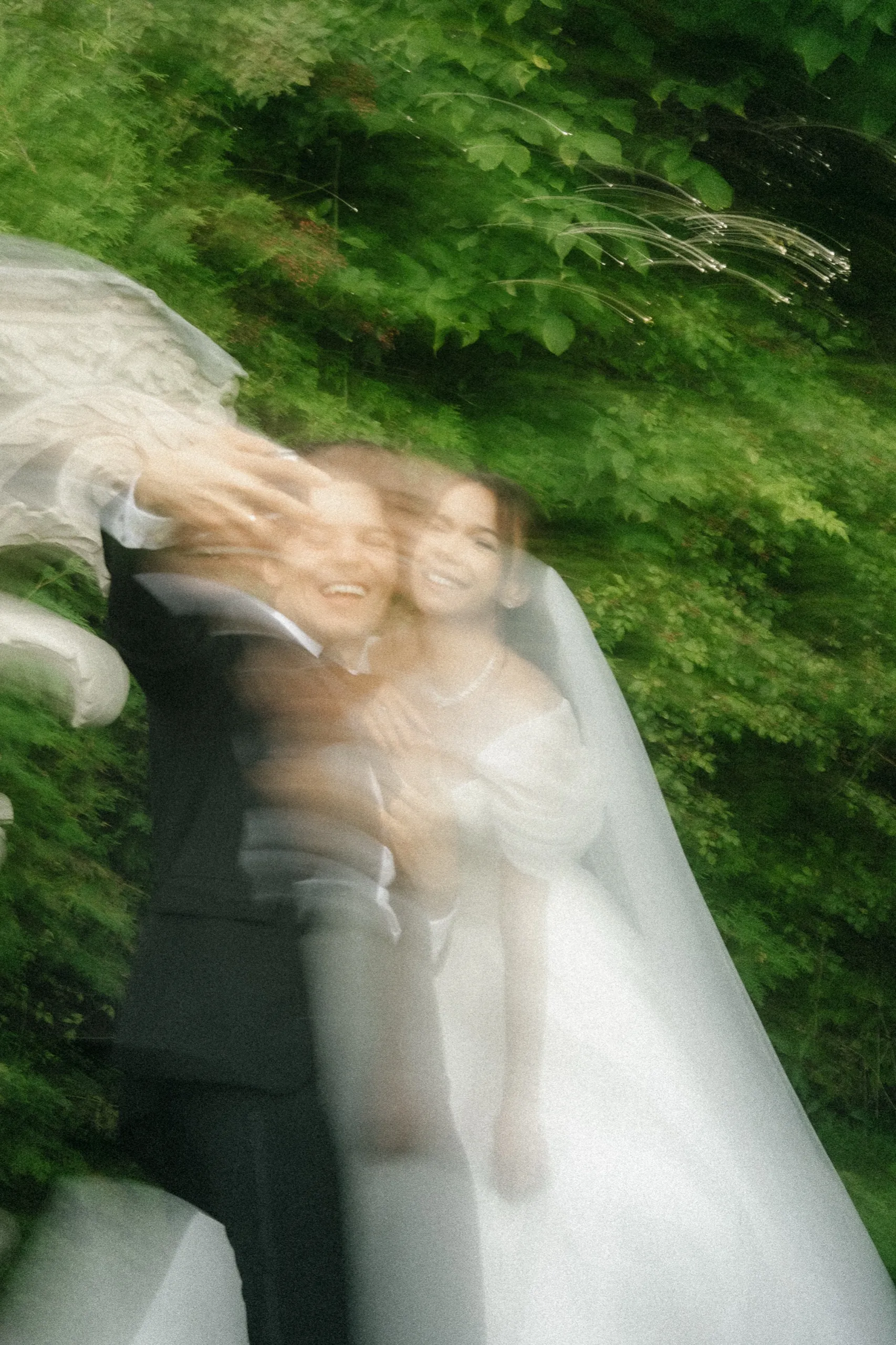 Groom laughing as the veil whips across the frame in motion blur, by AD Photography