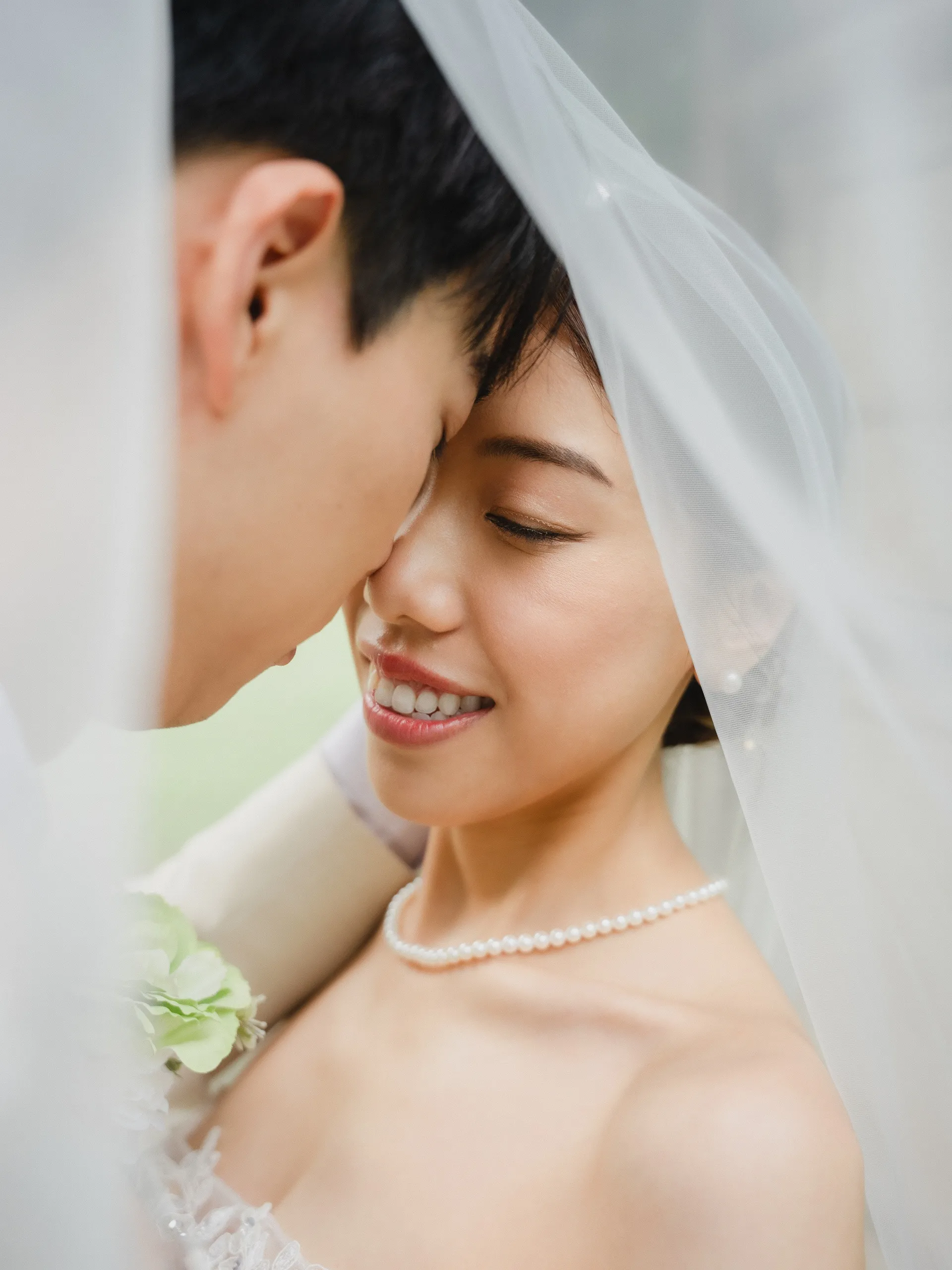 Shot through the veil, Nelson resting his forehead against a smiling Josie, by AD Photography