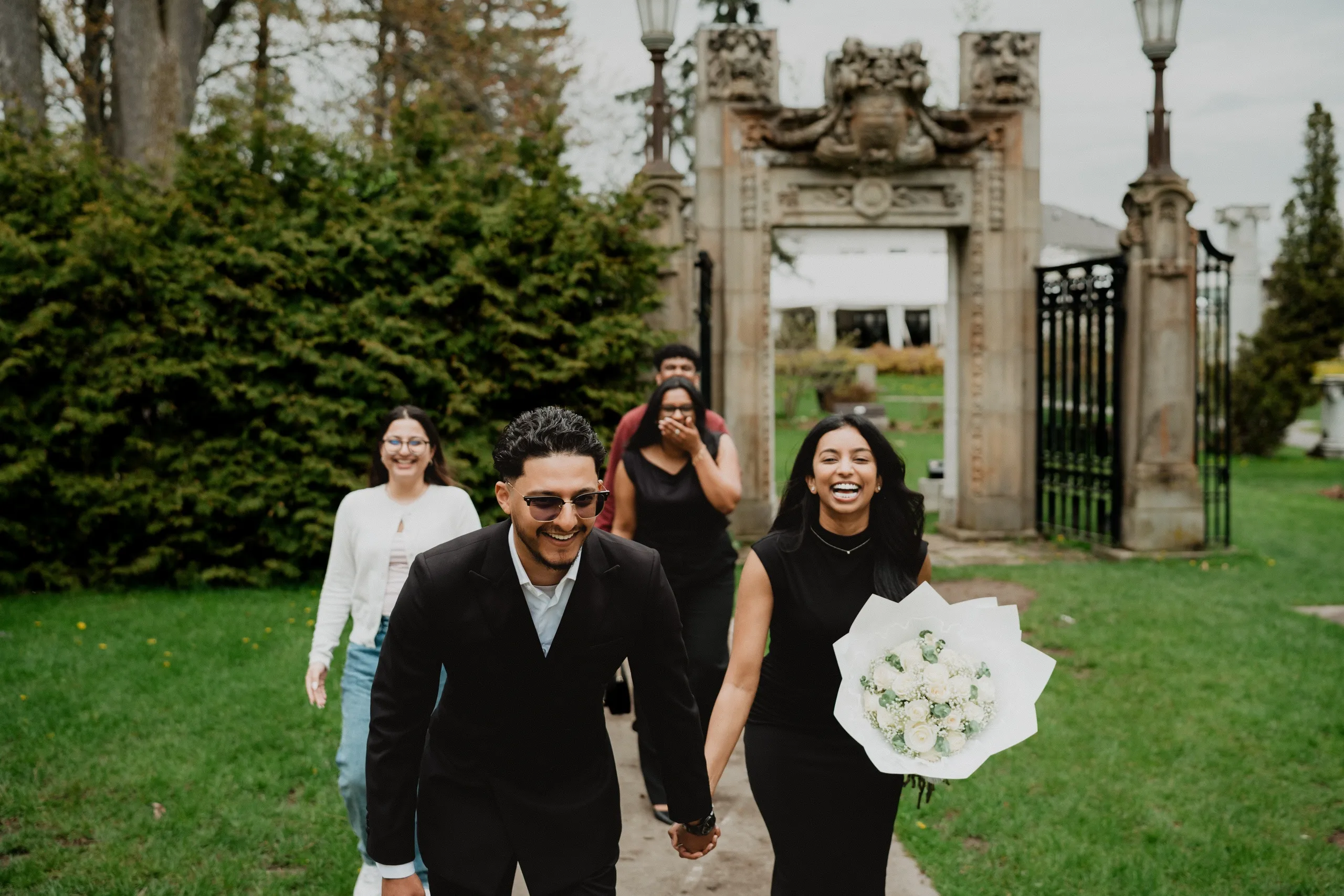 Friends following Lavina and Raeed up the path through the stone gate at Guild Park and Gardens, by AD Photography