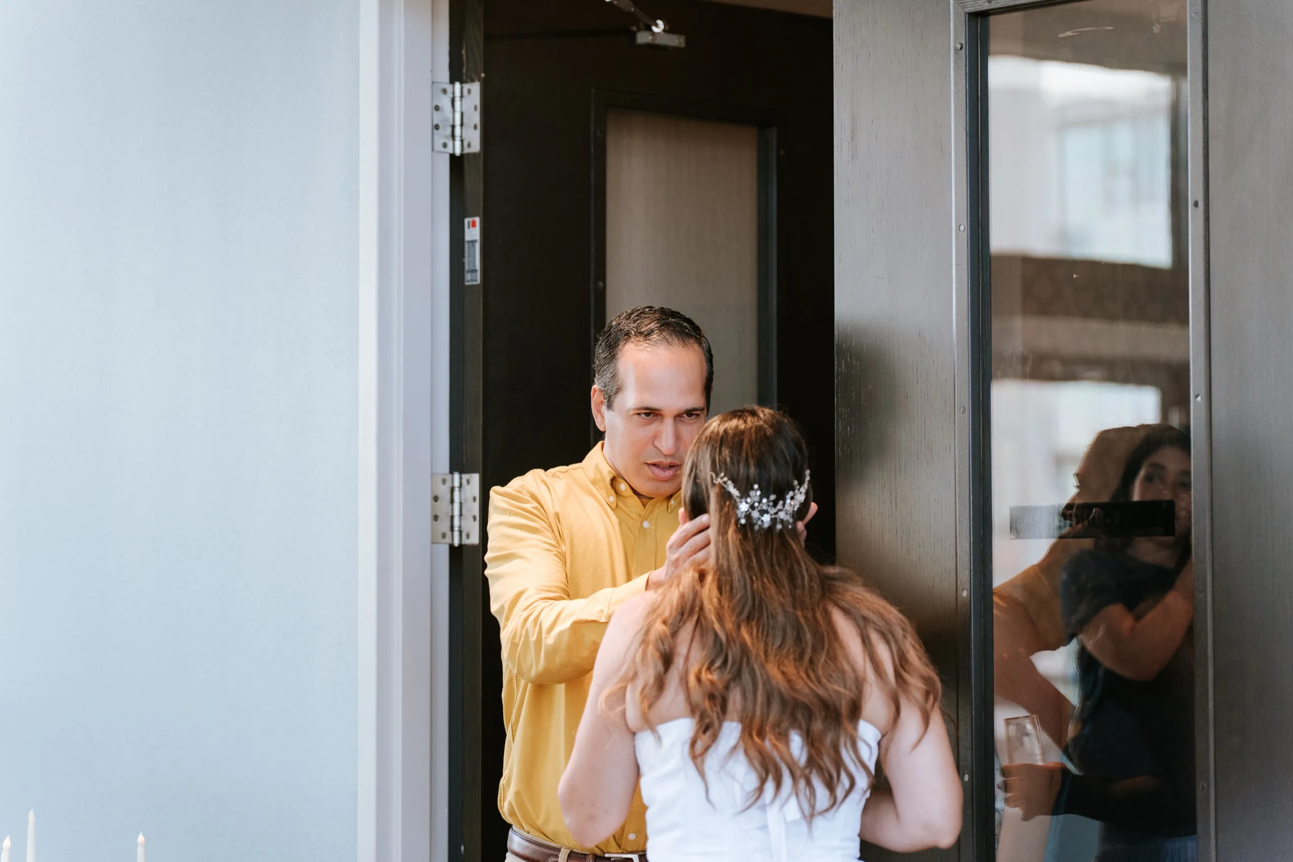 A guest in a yellow shirt greets a family member at the door, framed by the entry, by AD Photography