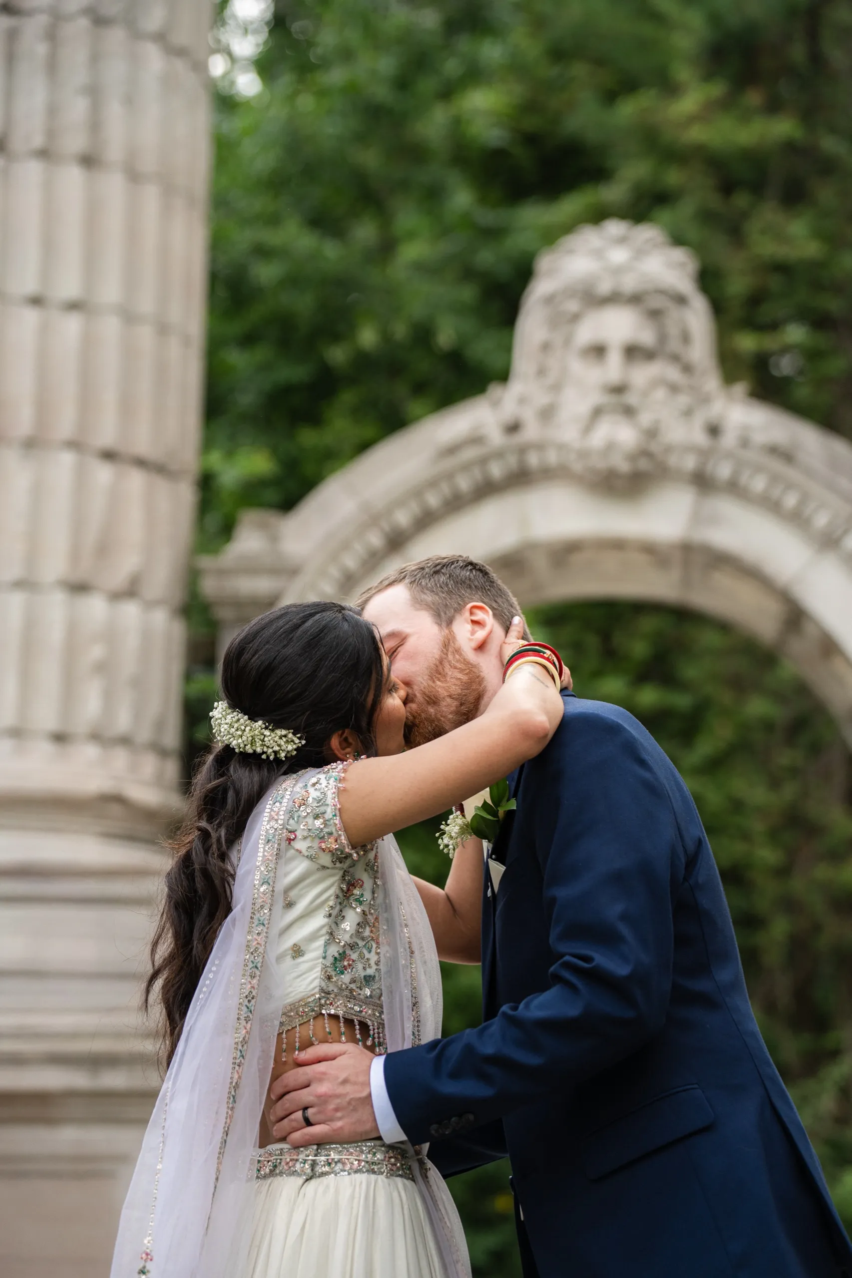 Nidhi and Derek share their first kiss as a married couple beneath the stone arch., by AD Photography