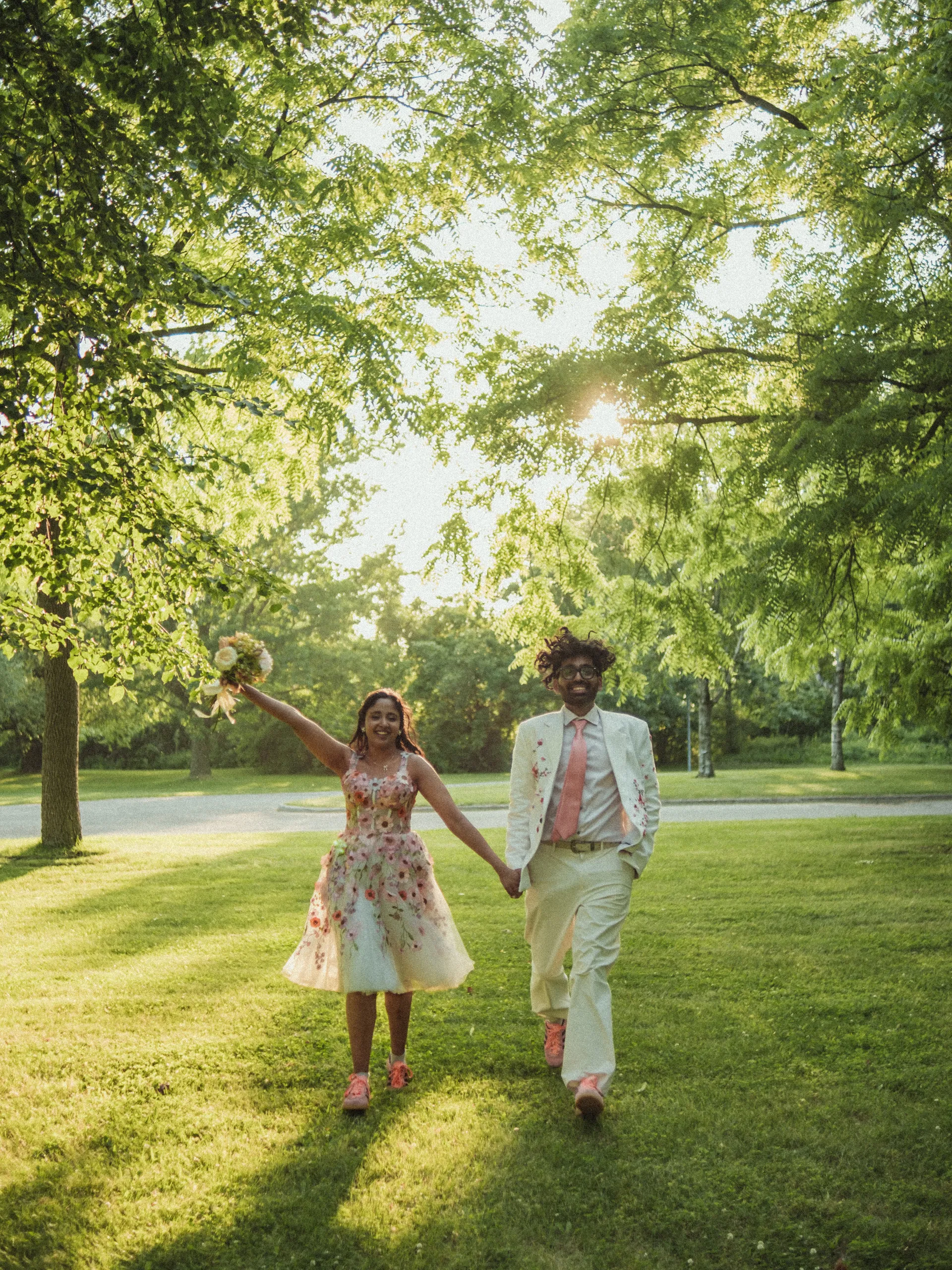Harsh and Payal walking toward camera through a tunnel of trees on the Toronto Islands, by AD Photography