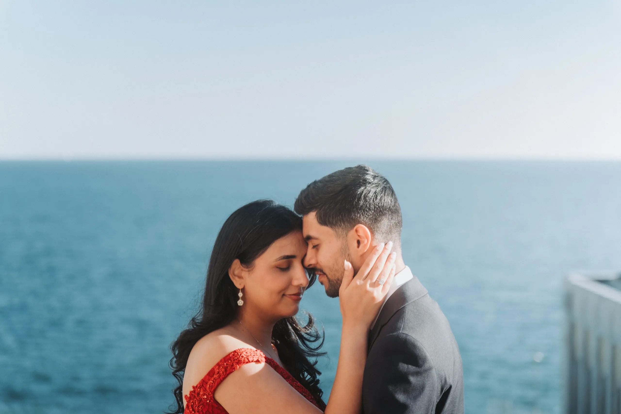 Foreheads together above Lake Ontario, Swati's ring hand resting on Saksham's cheek, by AD Photography