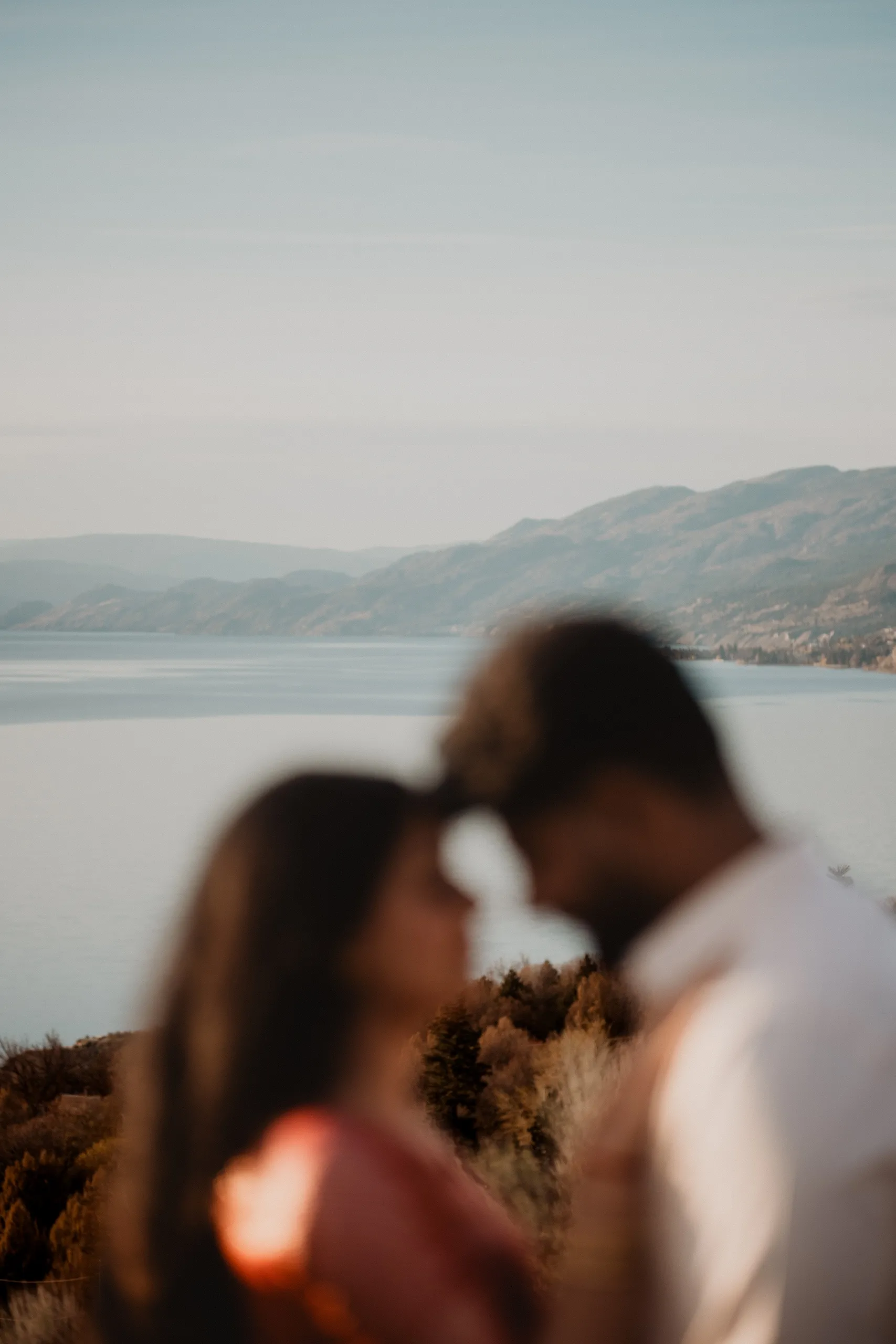 Soft blur of their foreheads touching with the Penticton hills sharp behind them, by AD Photography