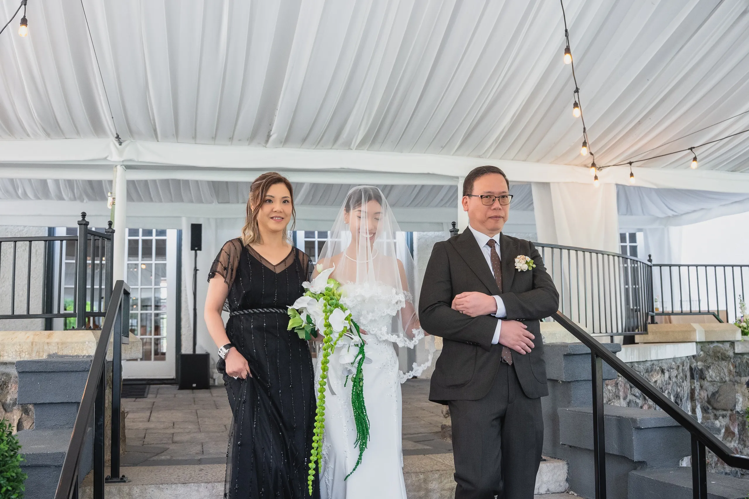 Josie in her veil escorted down the steps into the white draped ceremony tent, by AD Photography