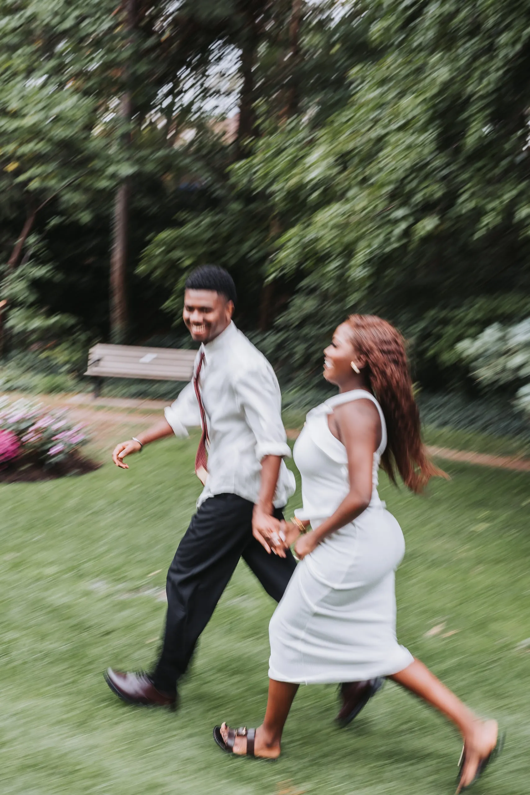 Richie and Aimee running hand in hand across the lawn in motion blur, both laughing, by AD Photography