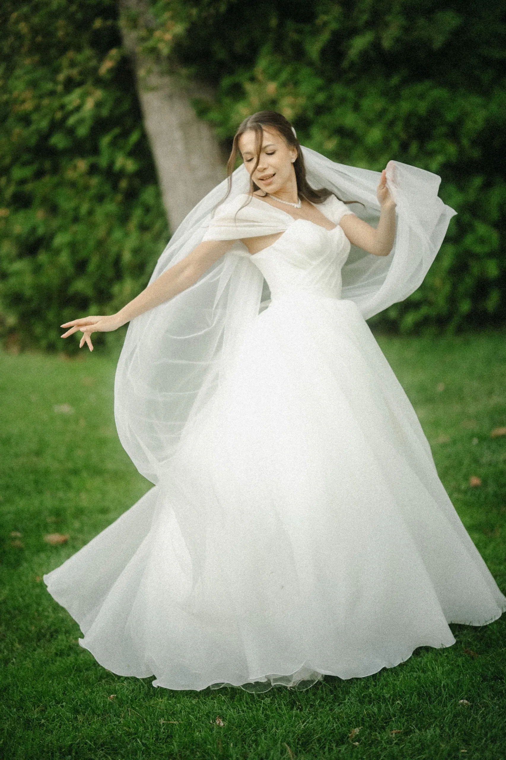 Bride mid twirl laughing with her eyes closed, veil lifted and gown flaring on the lawn at Guild Park, by AD Photography