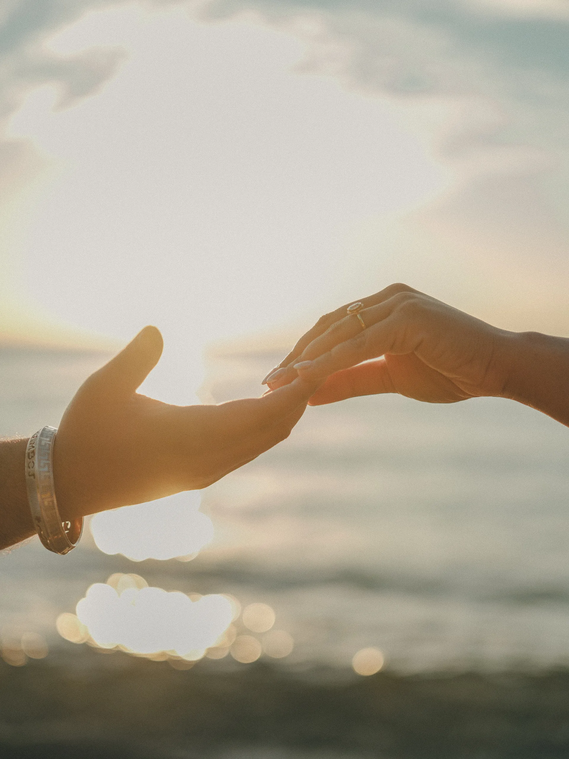 Maninder and Parneet's fingertips meet in the hazy glare of the low sun, her ring catching the light, by AD Photography
