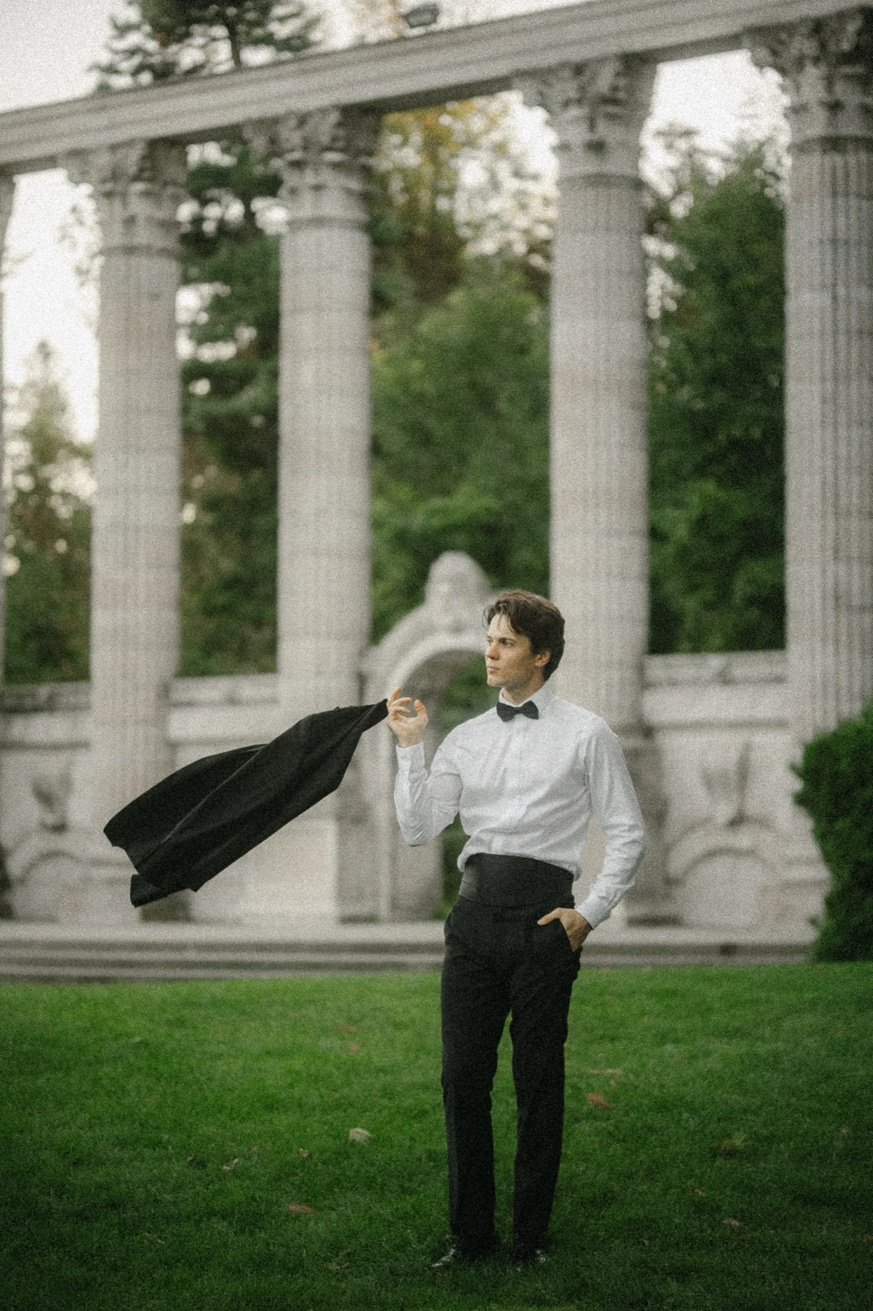 Groom flinging his tuxedo jacket through the air in front of the colonnade, by AD Photography