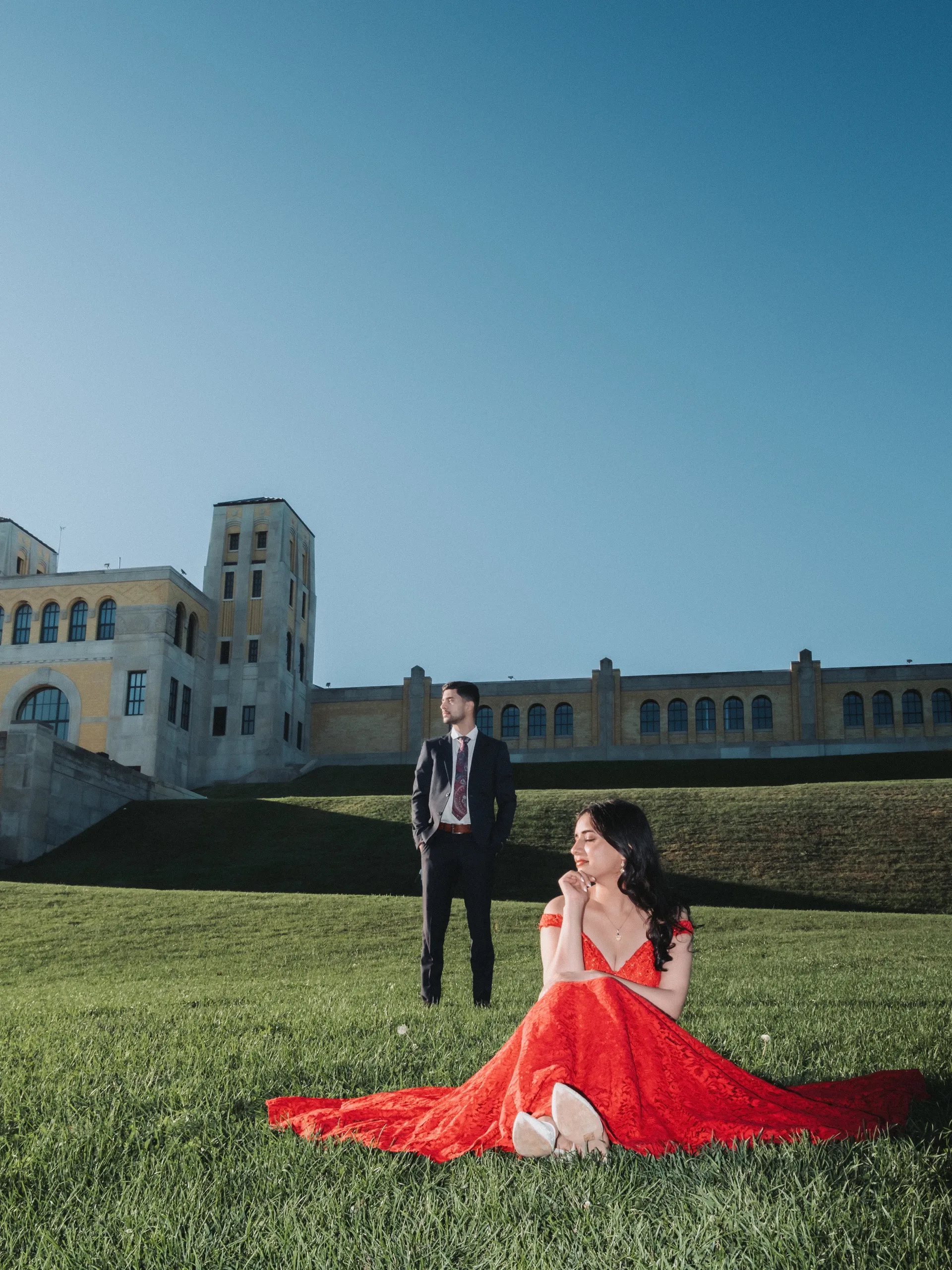 Editorial flash portrait, Swati seated in red lace while Saksham stands by the deco tower, by AD Photography