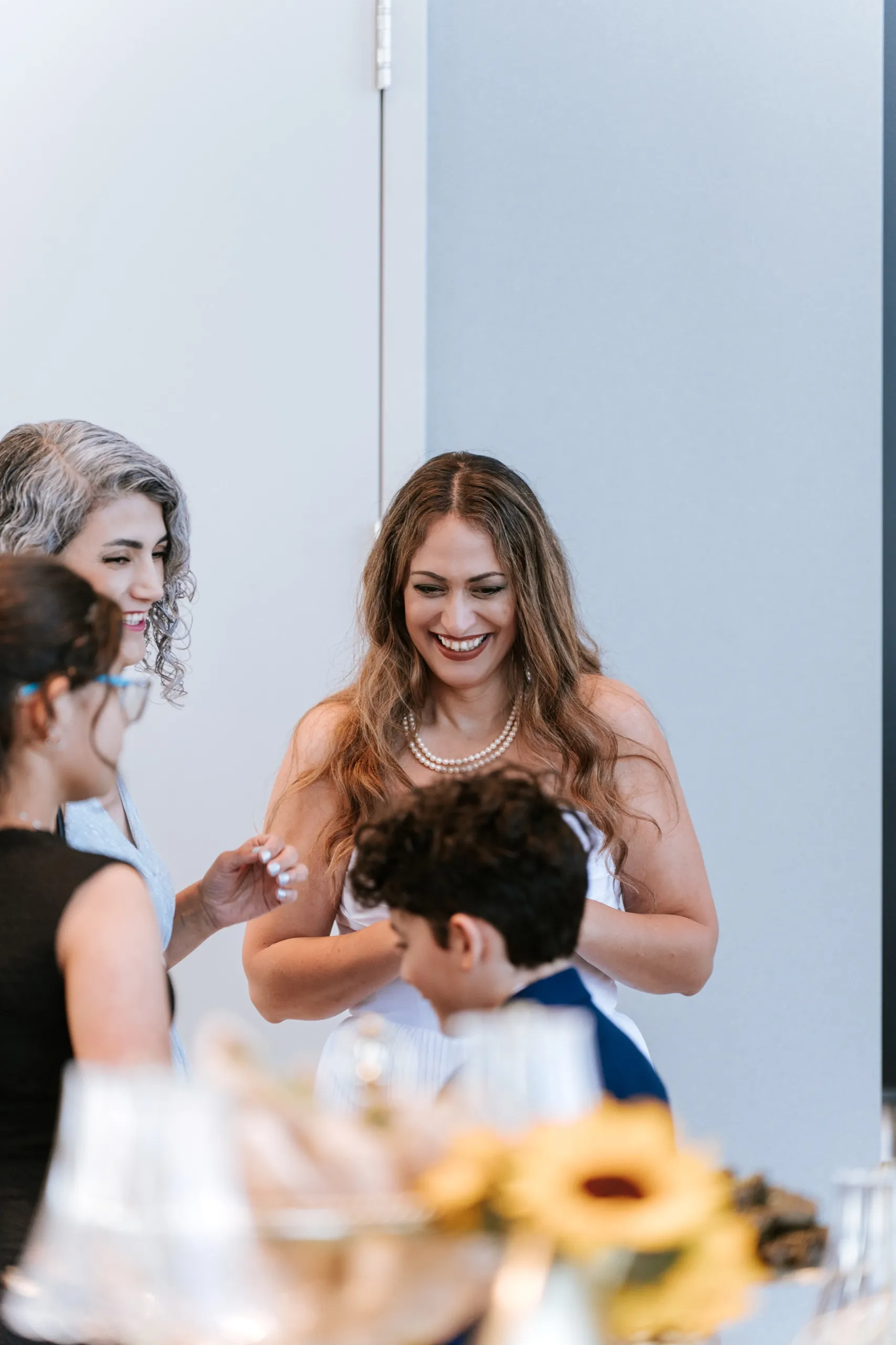 Zoha laughs with the children and an older family member beside the sunflower centrepiece, by AD Photography