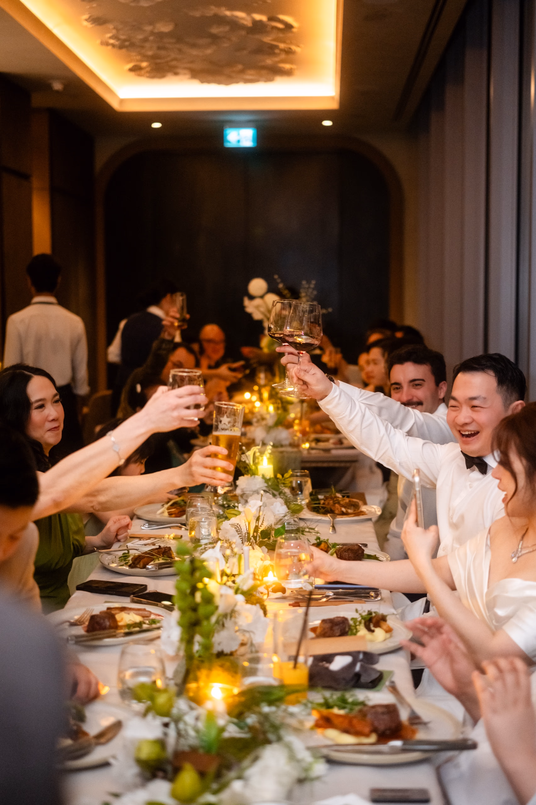 Grace and Giovanni's wedding toast at Aera Toronto, long Italian dinner table glowing under candlelight on the 38th floor of CIBC Square, by AD Photography