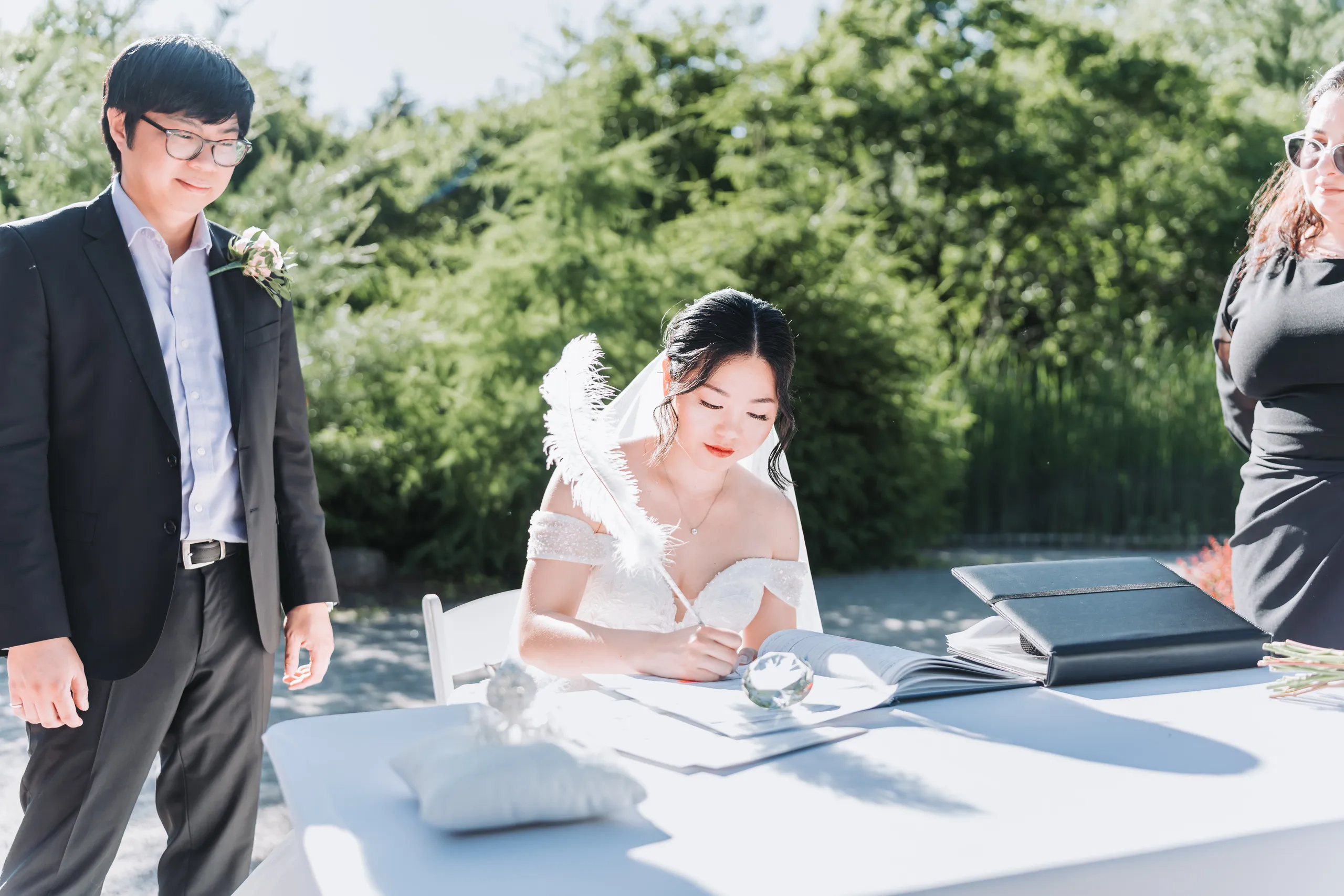 Signing the marriage register with a white feather quill outdoors at the Niagara Parks Botanical Gardens, by AD Photography