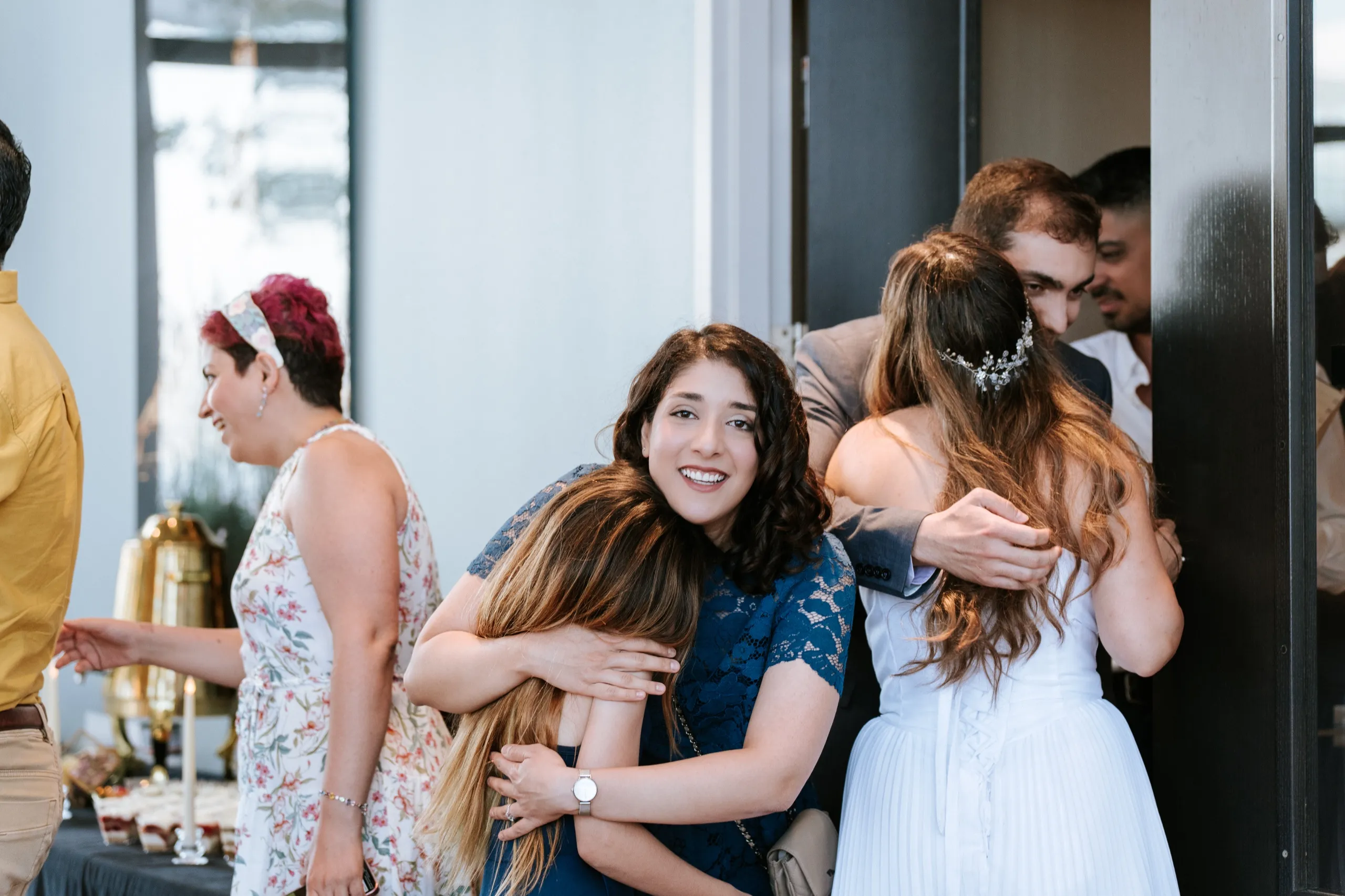 Guests hug in the doorway as Zoha greets family arriving for the celebration, by AD Photography