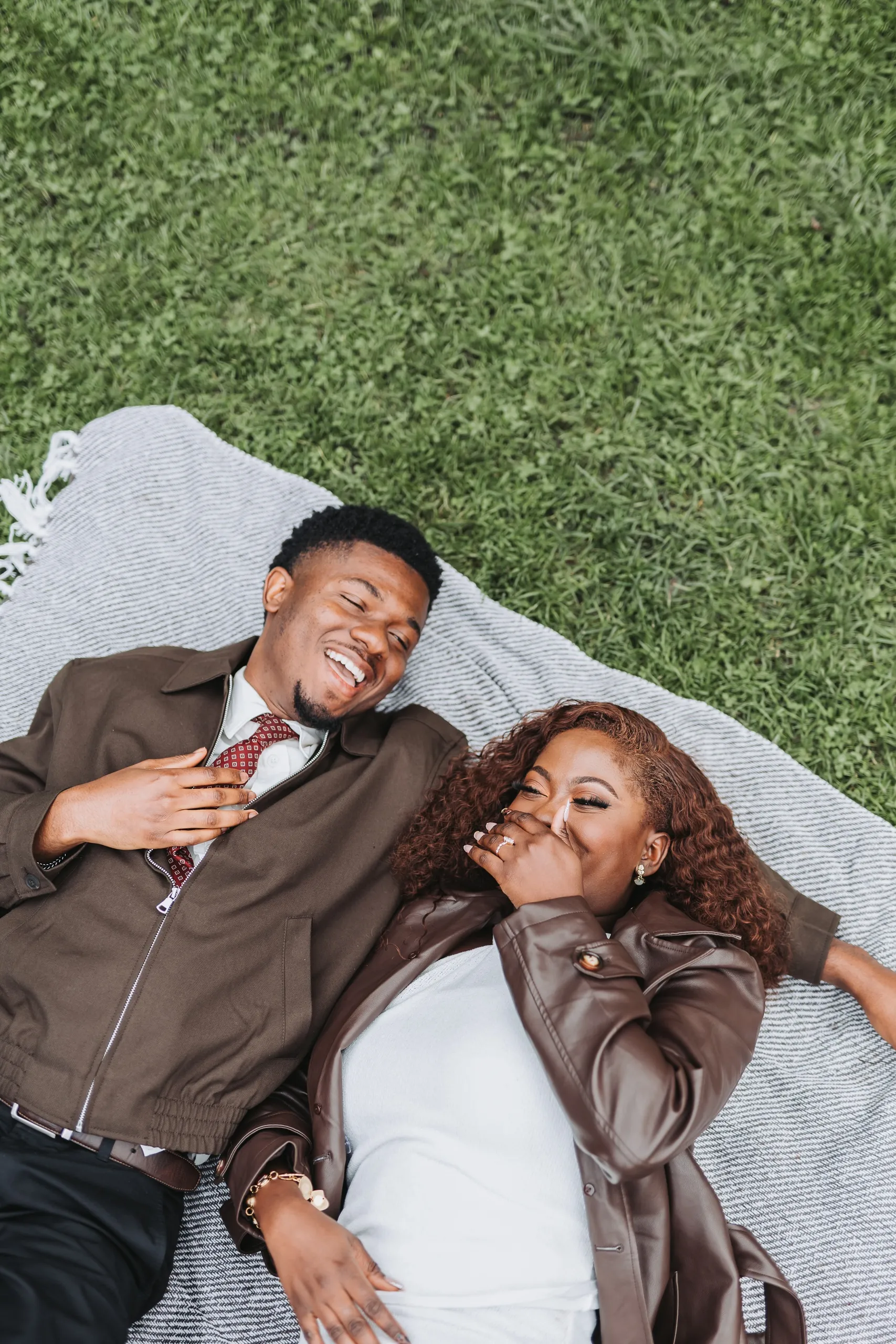 Richie and Aimee lying on a blanket in the grass laughing, seen from above, by AD Photography