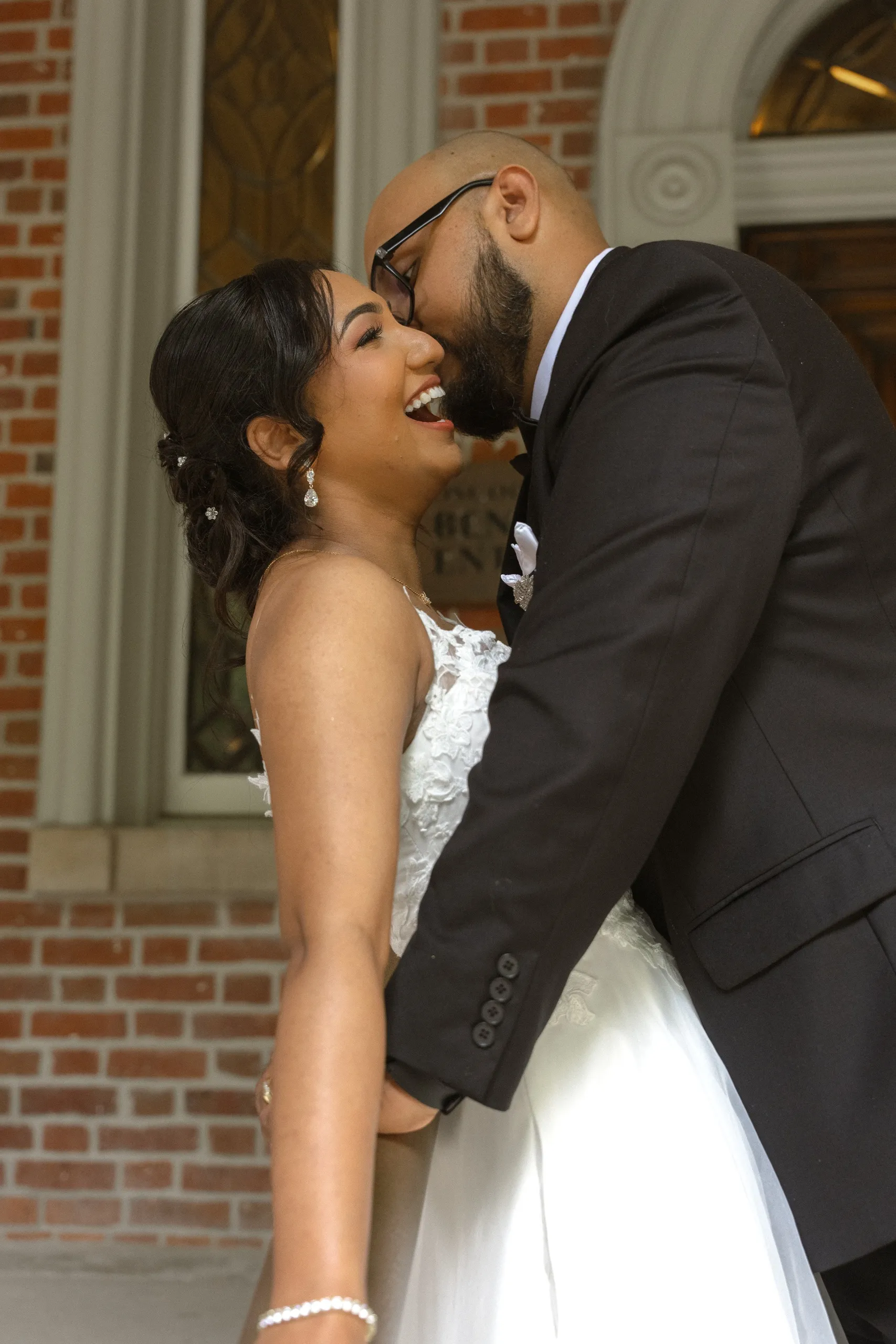 Bride laughs against the brick wall at the Osgoode Hall benchers entrance, by AD Photography