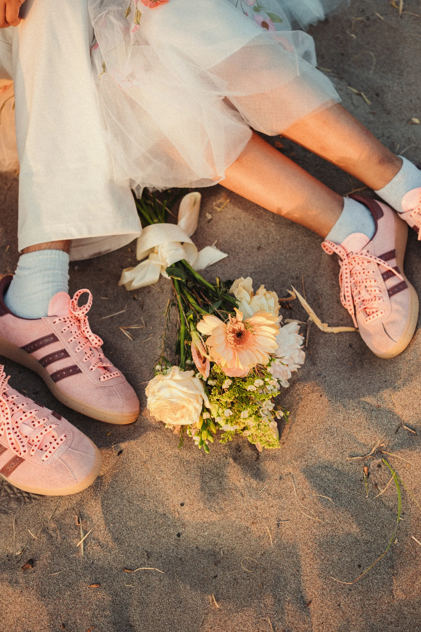 Flat lay of the couple's pink sneakers and Payal's bouquet on the sand, Toronto Islands, by AD Photography