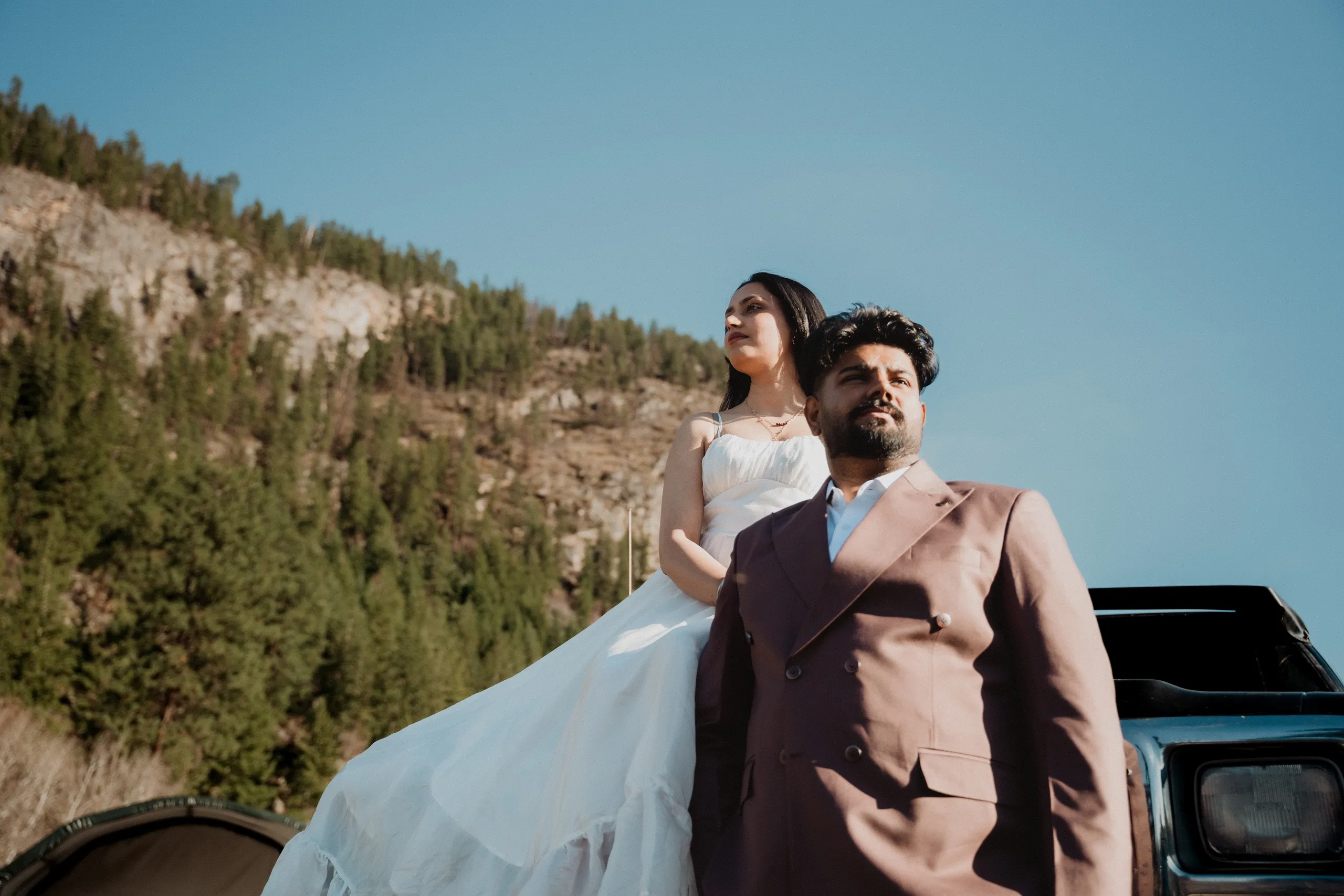 Mehak and Kamal against a vintage truck with a pine slope rising behind them, by AD Photography