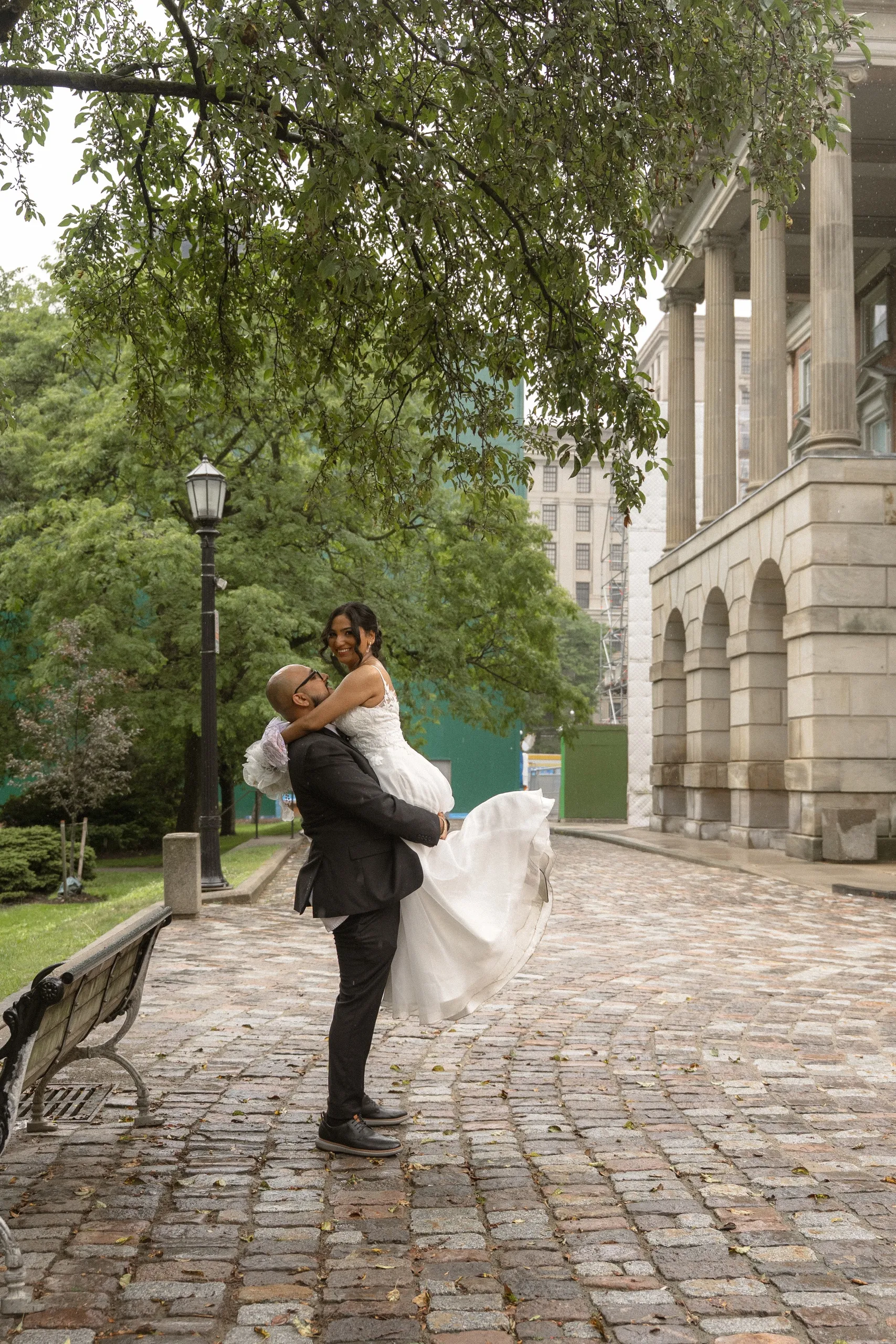 Groom lifts the bride on the cobblestone lane beside Osgoode Hall, by AD Photography