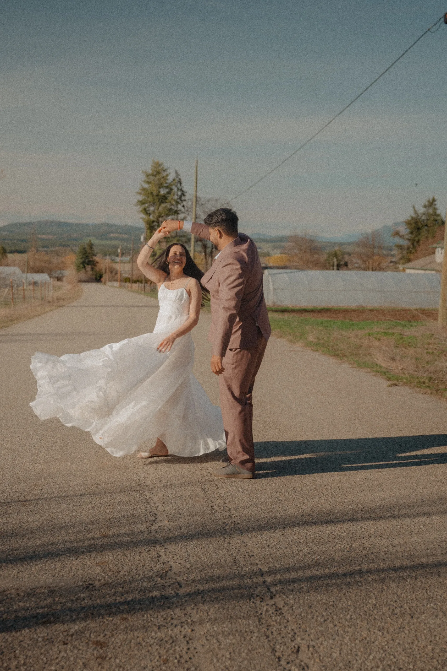 Grainy hazy frame of Kamal spinning the bride on an empty farm road, by AD Photography