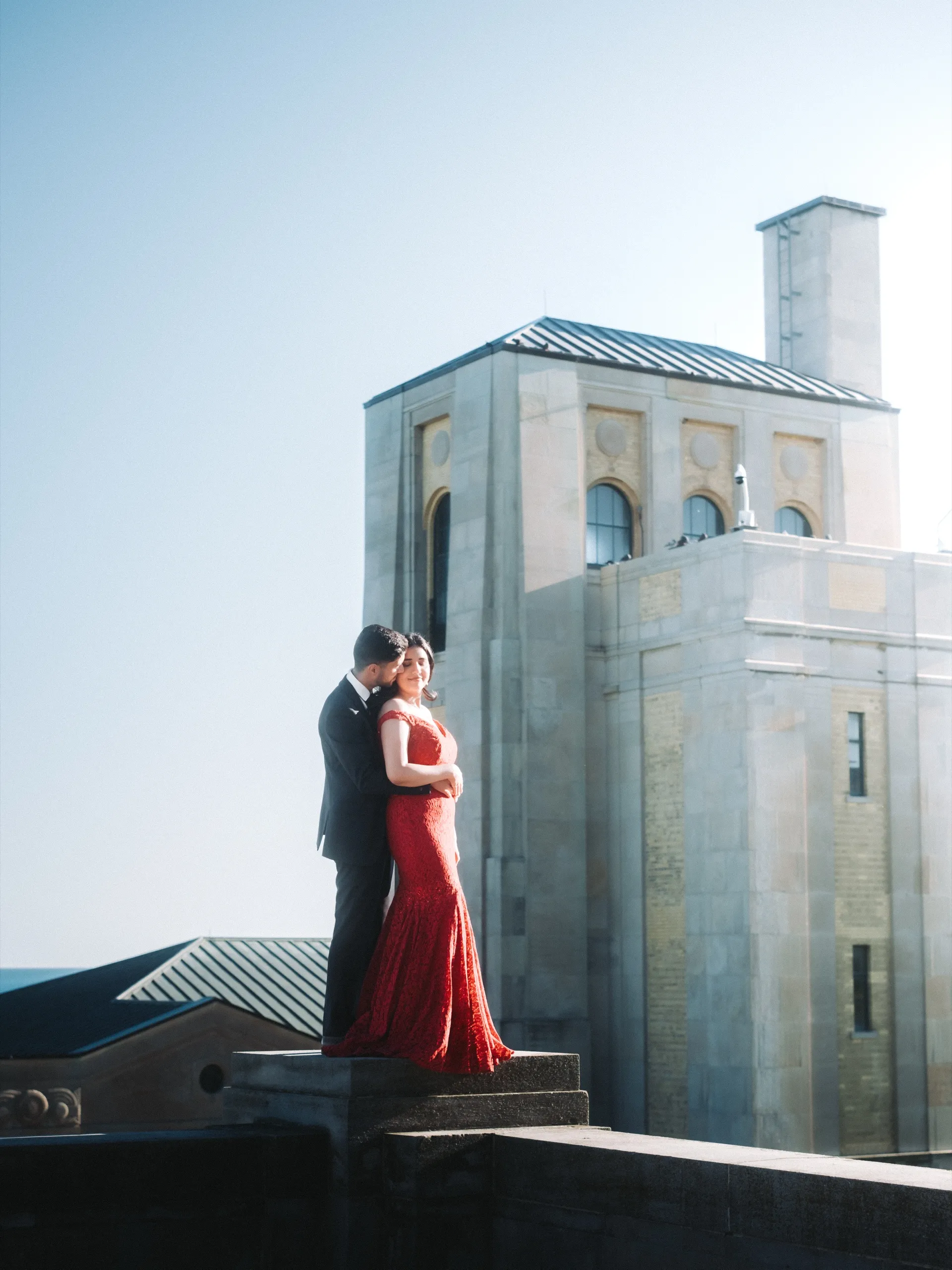 Hazy warm frame of Saksham holding Swati from behind on the stone plinth, by AD Photography
