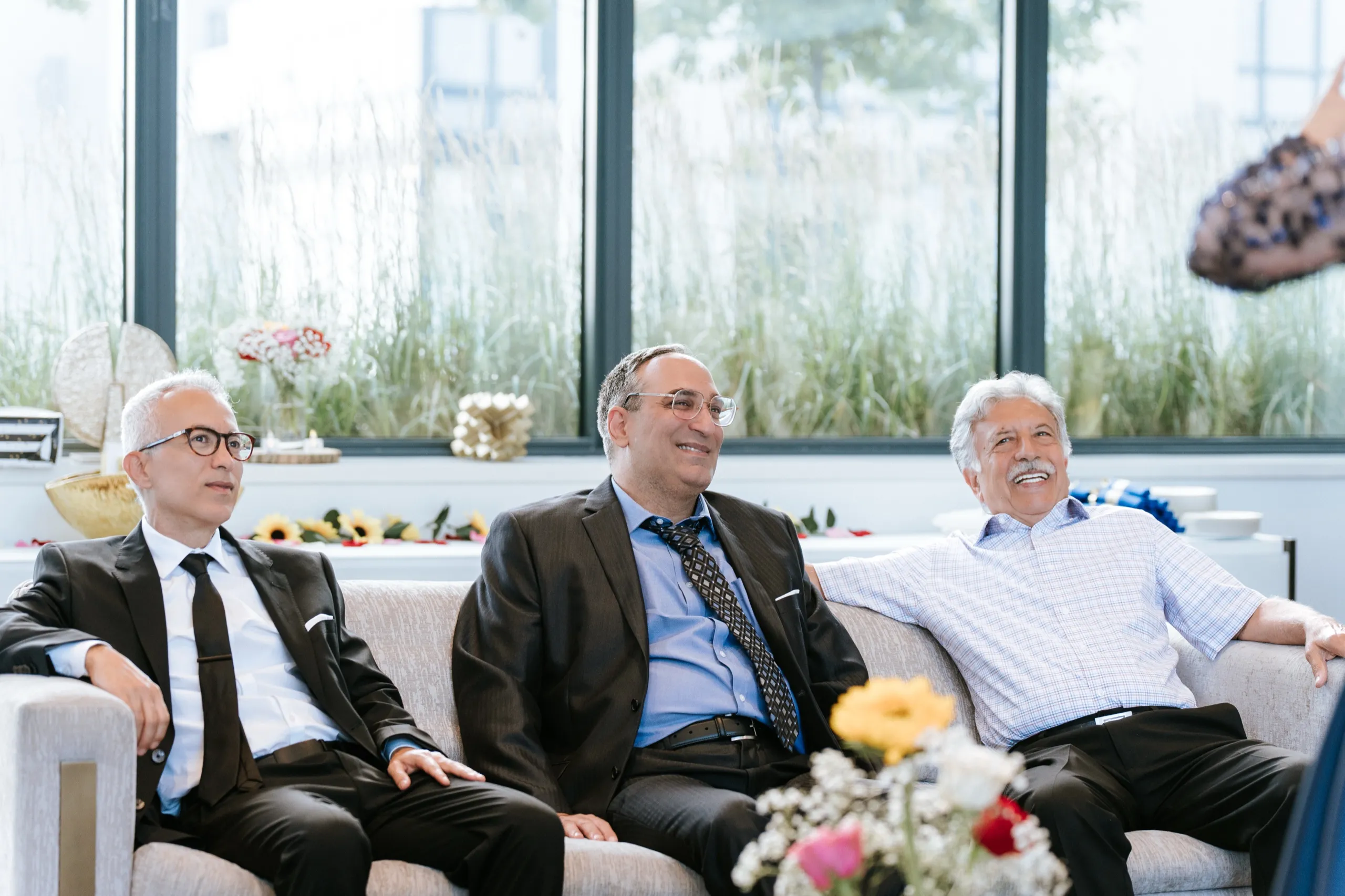 Three older family members settle on the white couch by the terrace windows, by AD Photography