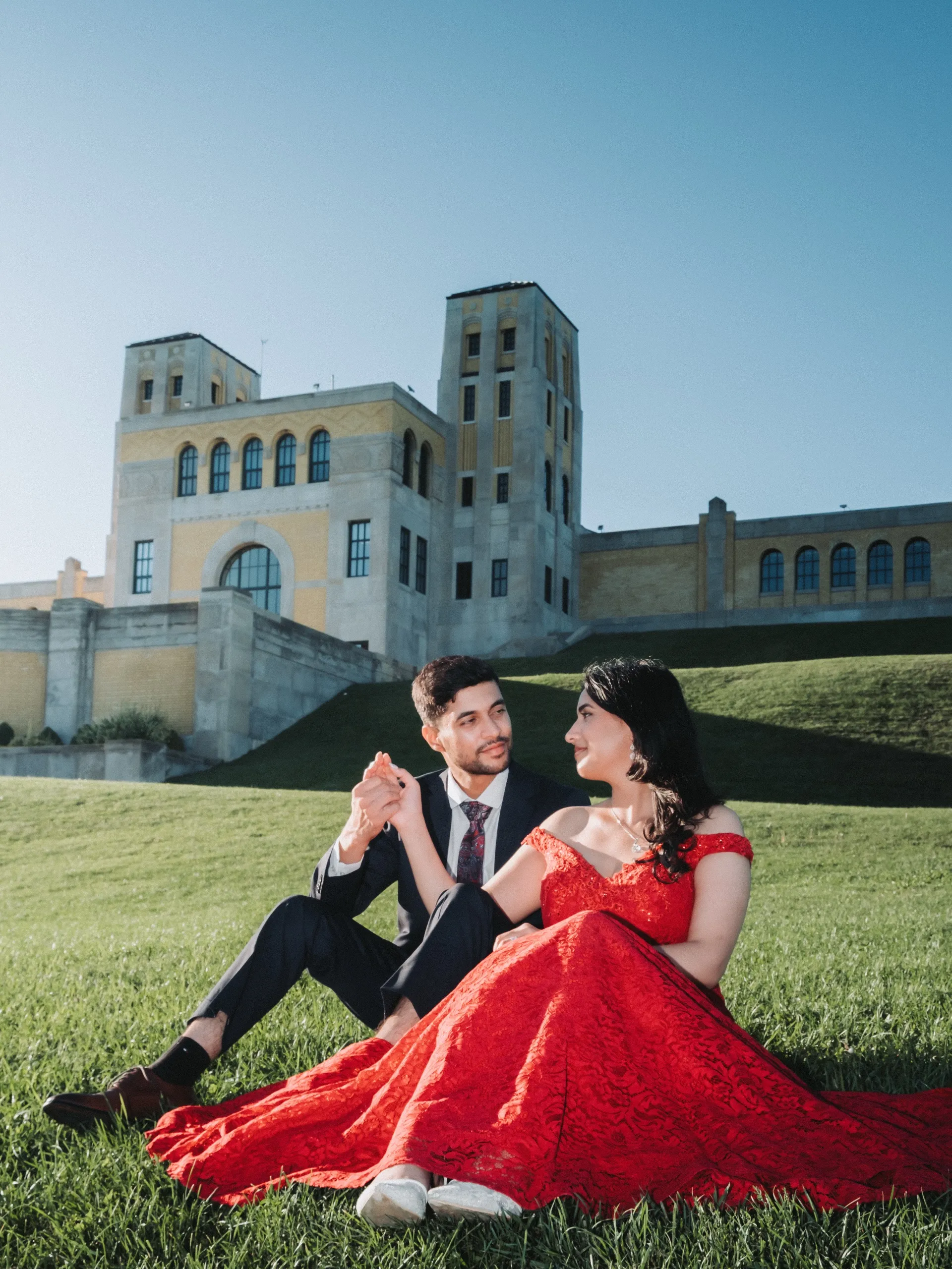 The couple sits together on the lawn beneath the castle like facade in Scarborough, by AD Photography