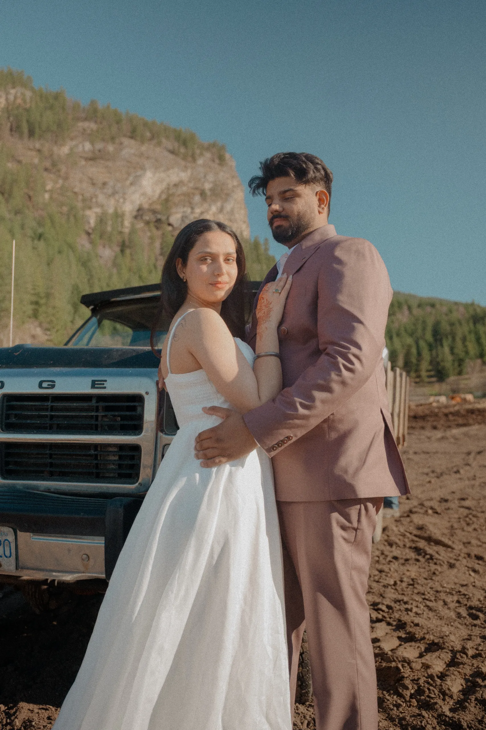 Grainy editorial frame of the couple beside a weathered blue Dodge farm truck, by AD Photography