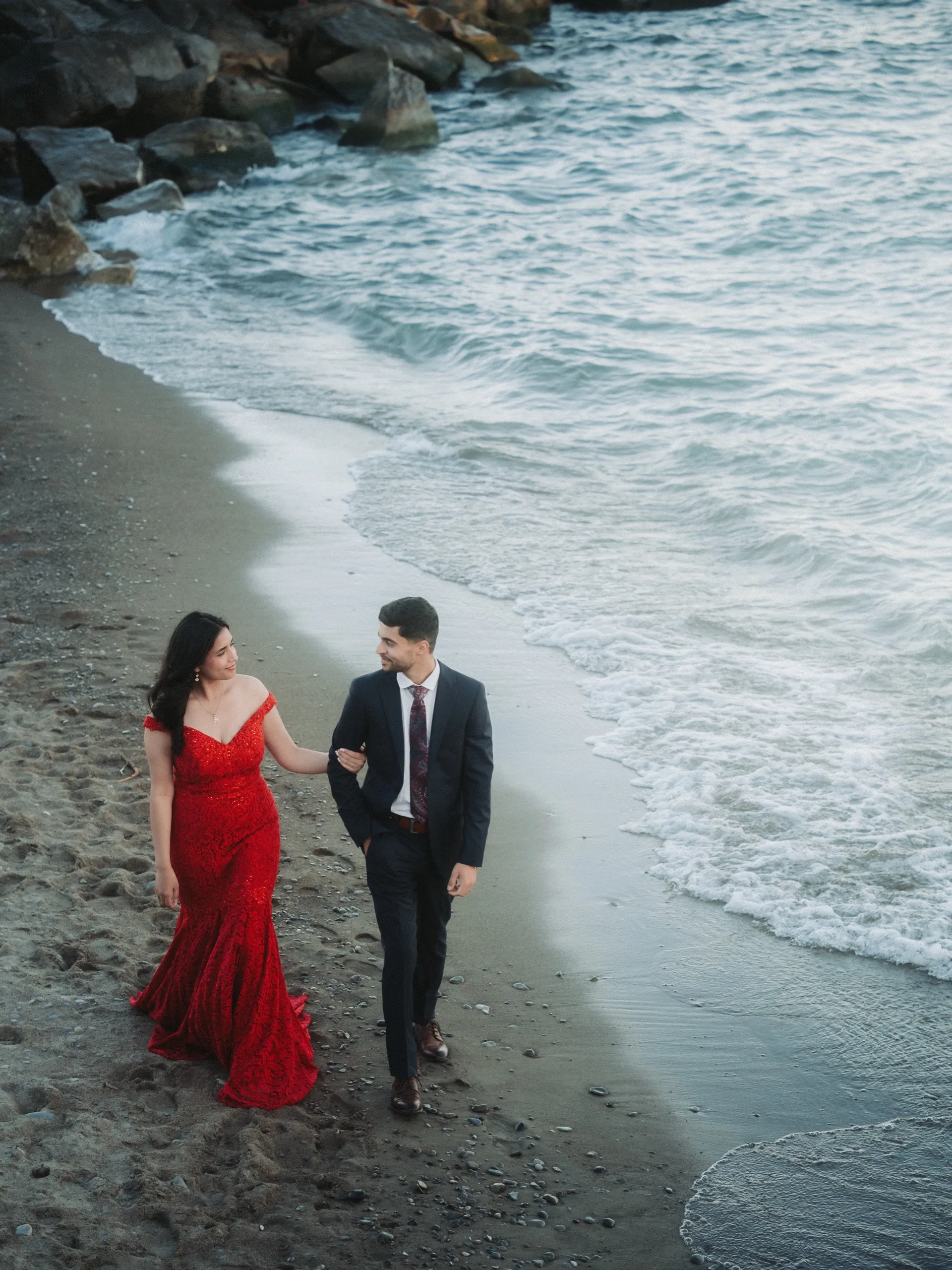 Blue hour walk along the surf below the bluffs of the plant, red gown against teal water, by AD Photography