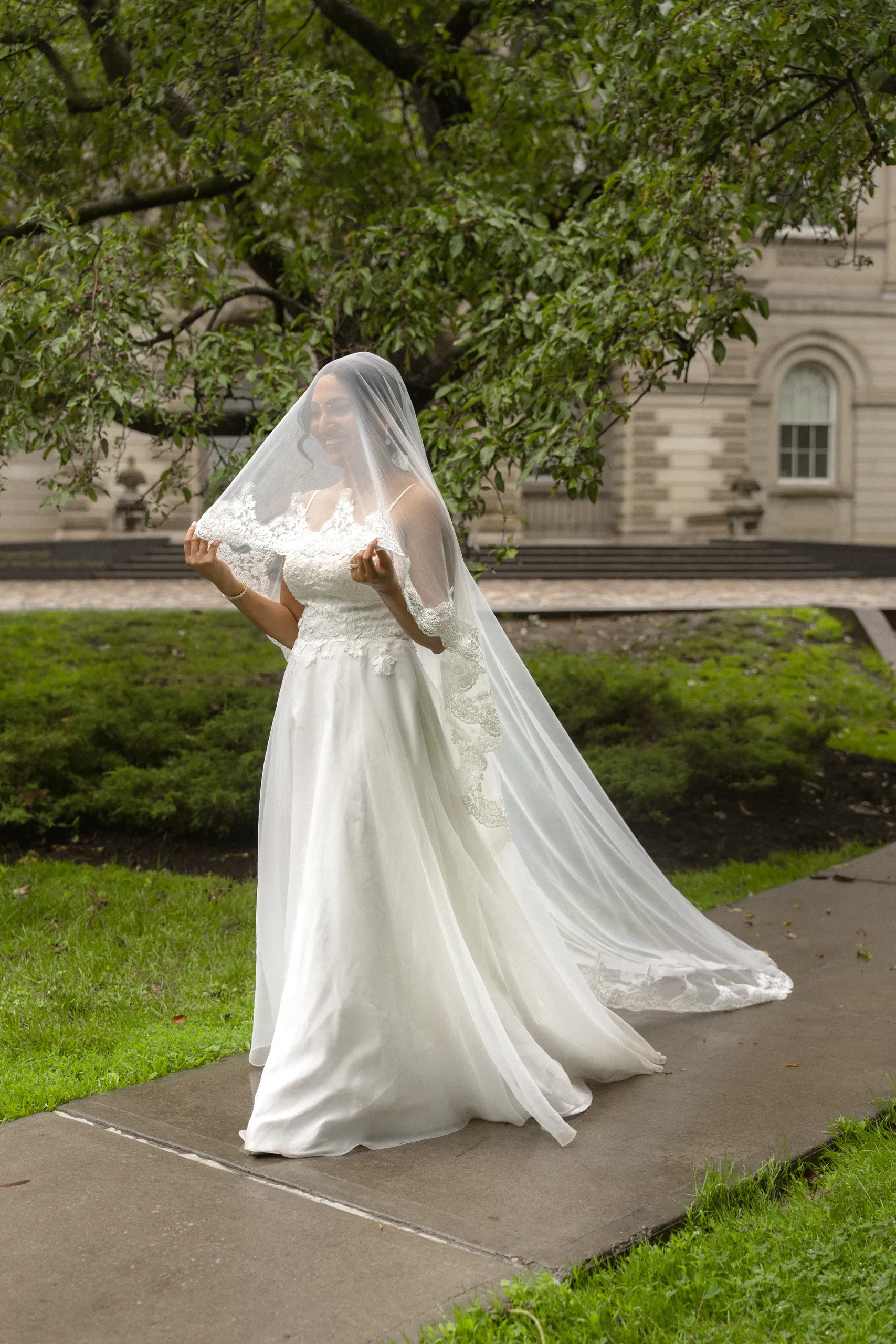 Bride holds her cathedral veil open on the Osgoode Hall lawn, by AD Photography