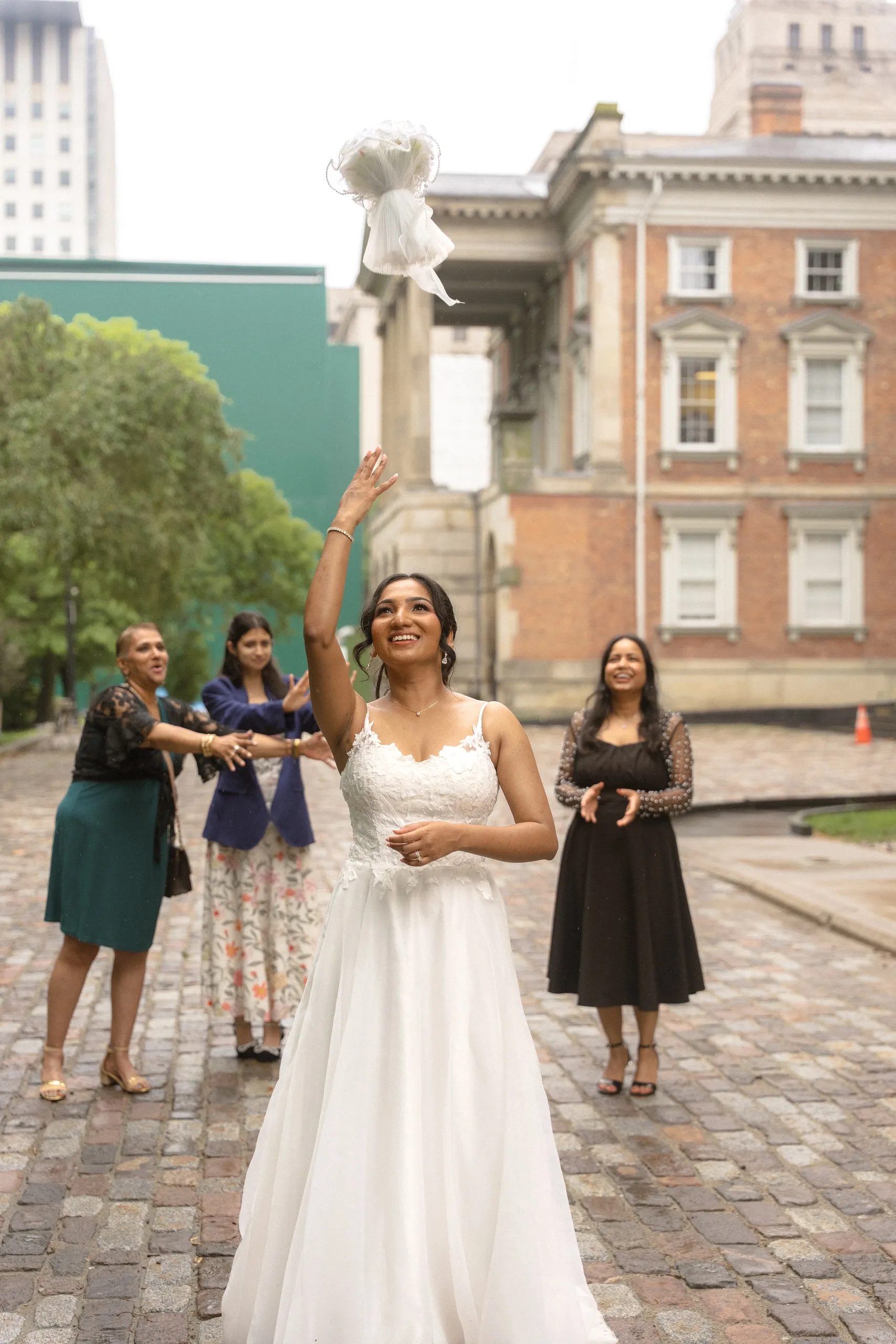 Bride tosses her bouquet on the cobblestones outside Osgoode Hall, by AD Photography