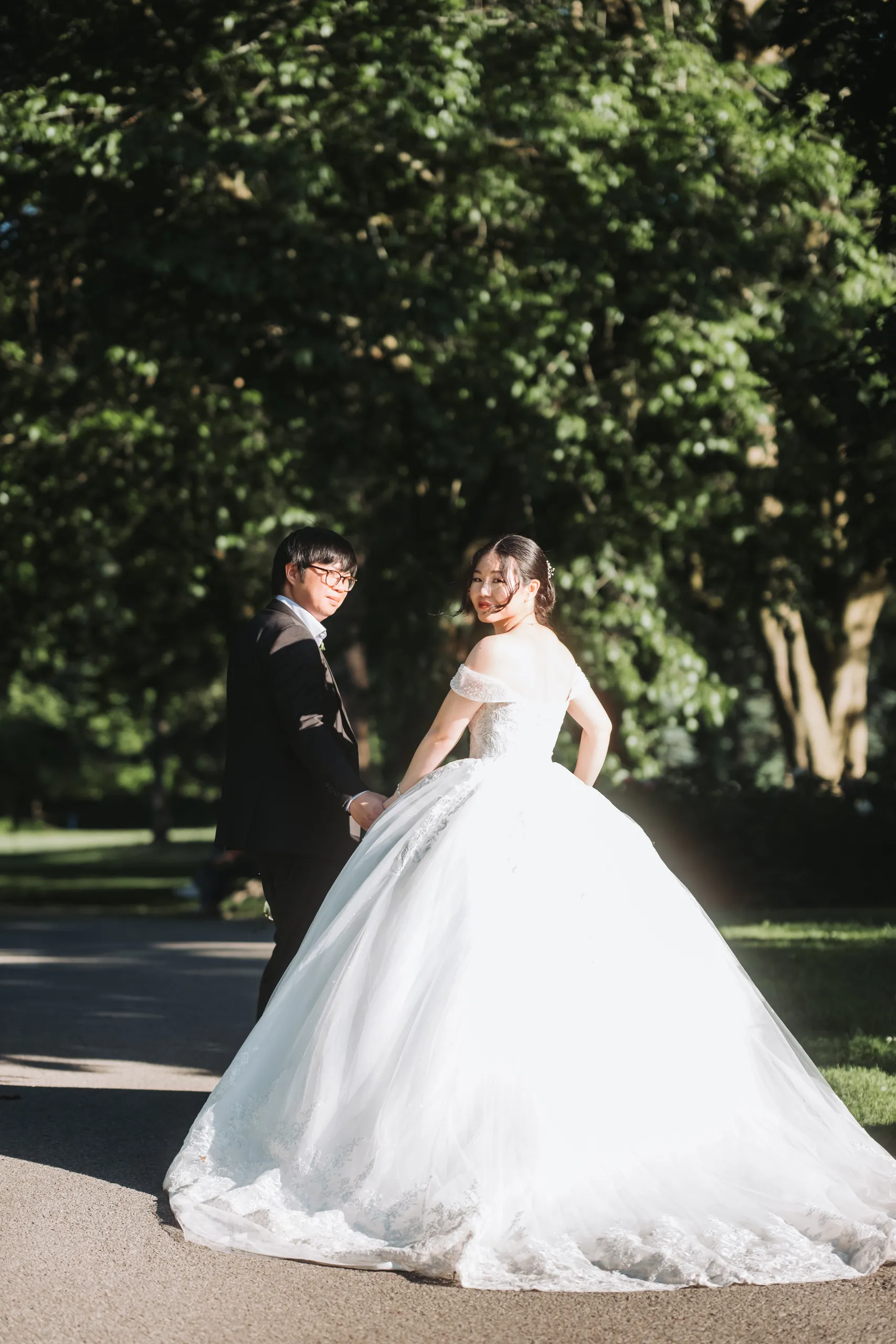 Karen glancing back over her shoulder in backlight on a tree lined path at the Botanical Gardens, by AD Photography