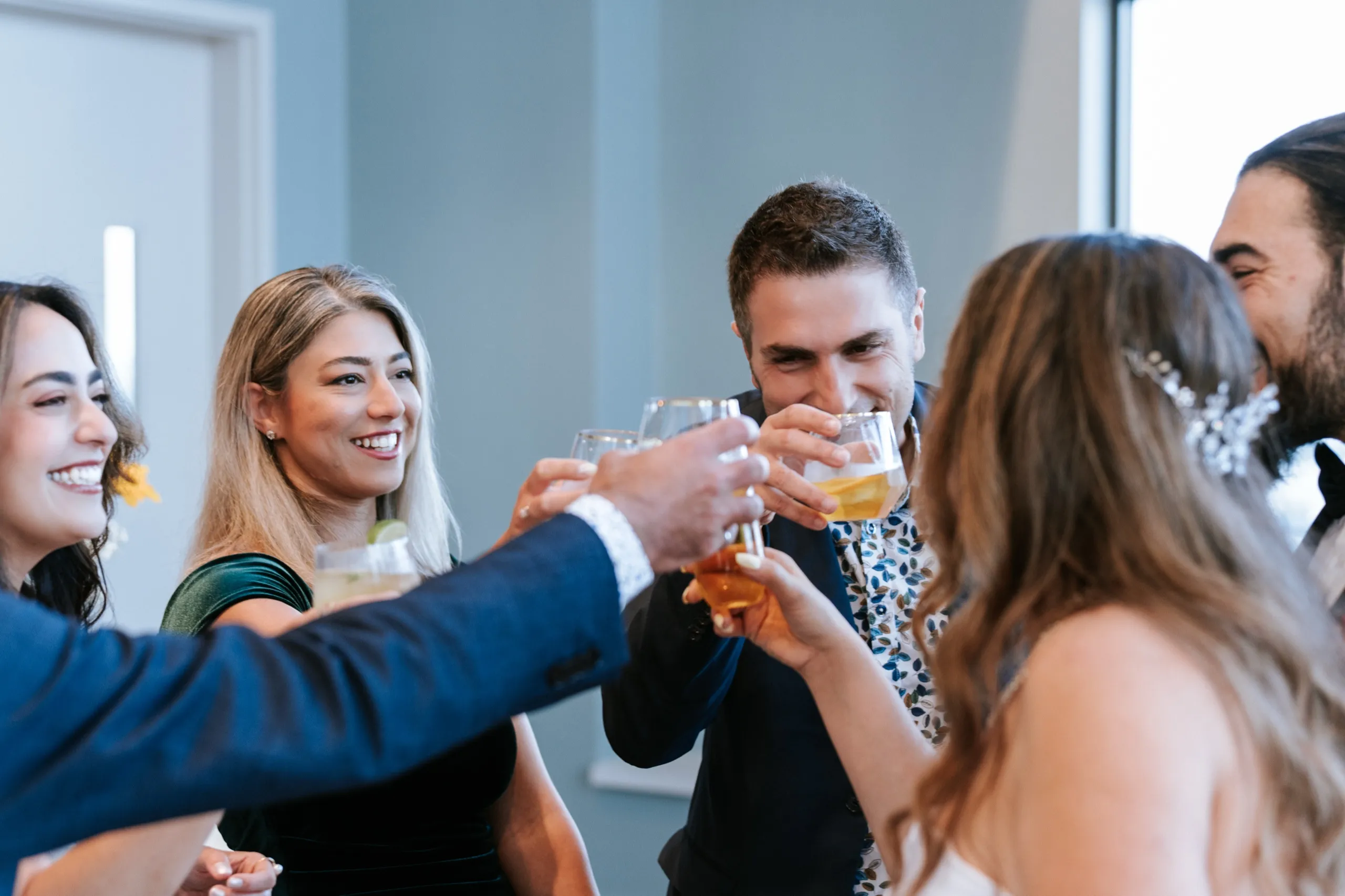Glasses meet in a toast to twenty years as guests crowd in around Zoha and Moe, by AD Photography