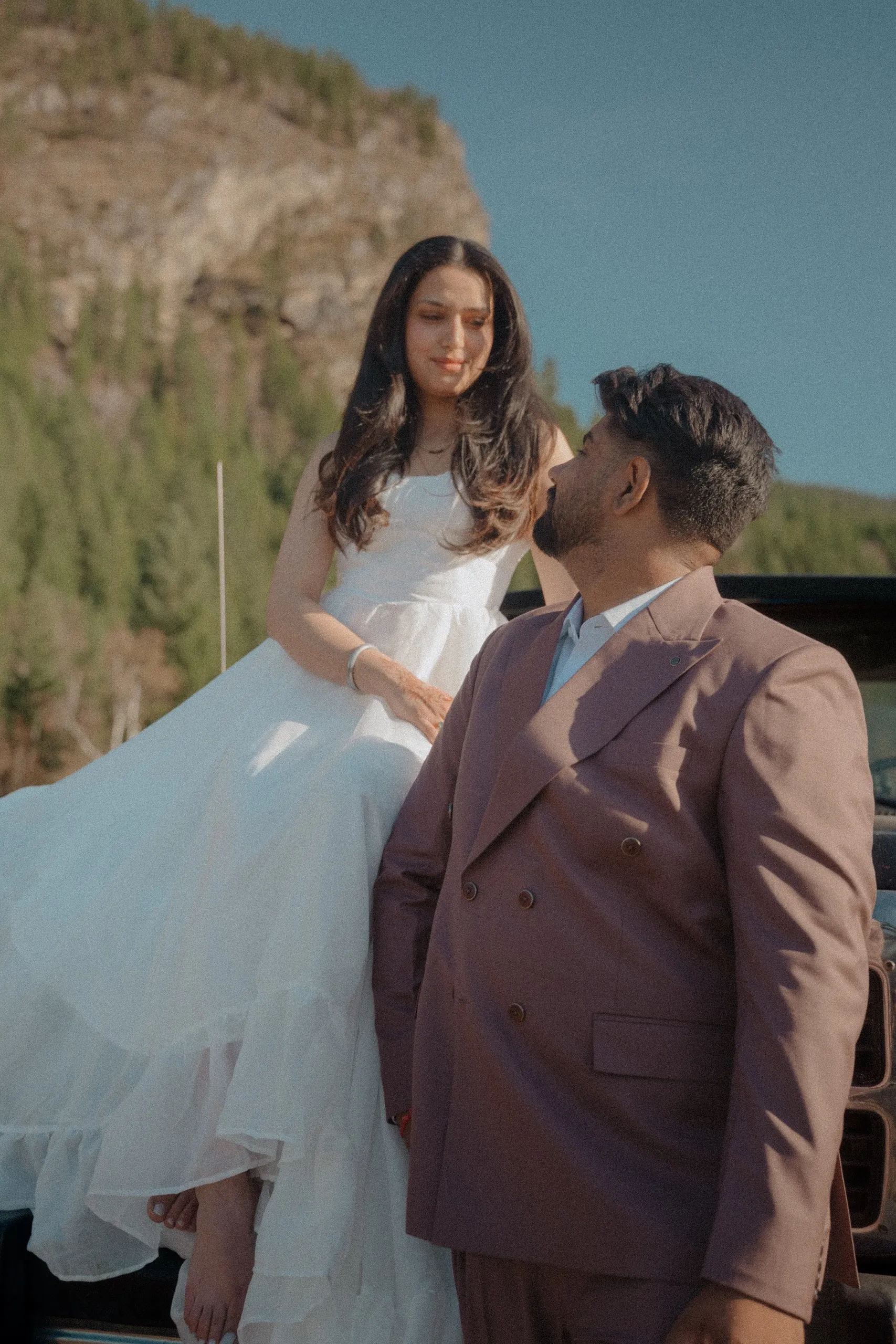 The bride perched on the truck bed while Kamal looks up at her, smiling, by AD Photography