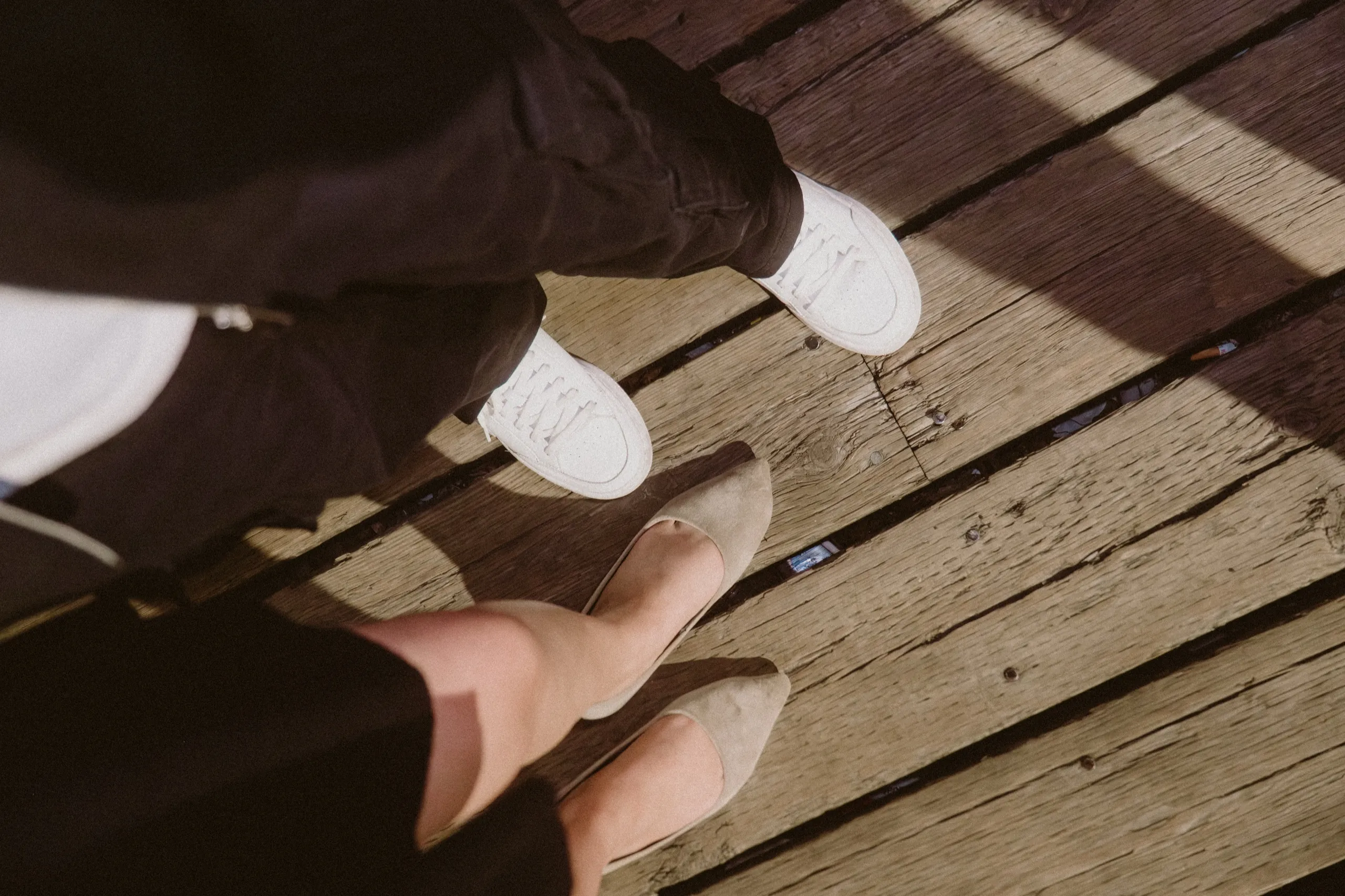 Film style detail of their shoes side by side on weathered boardwalk planks, by AD Photography